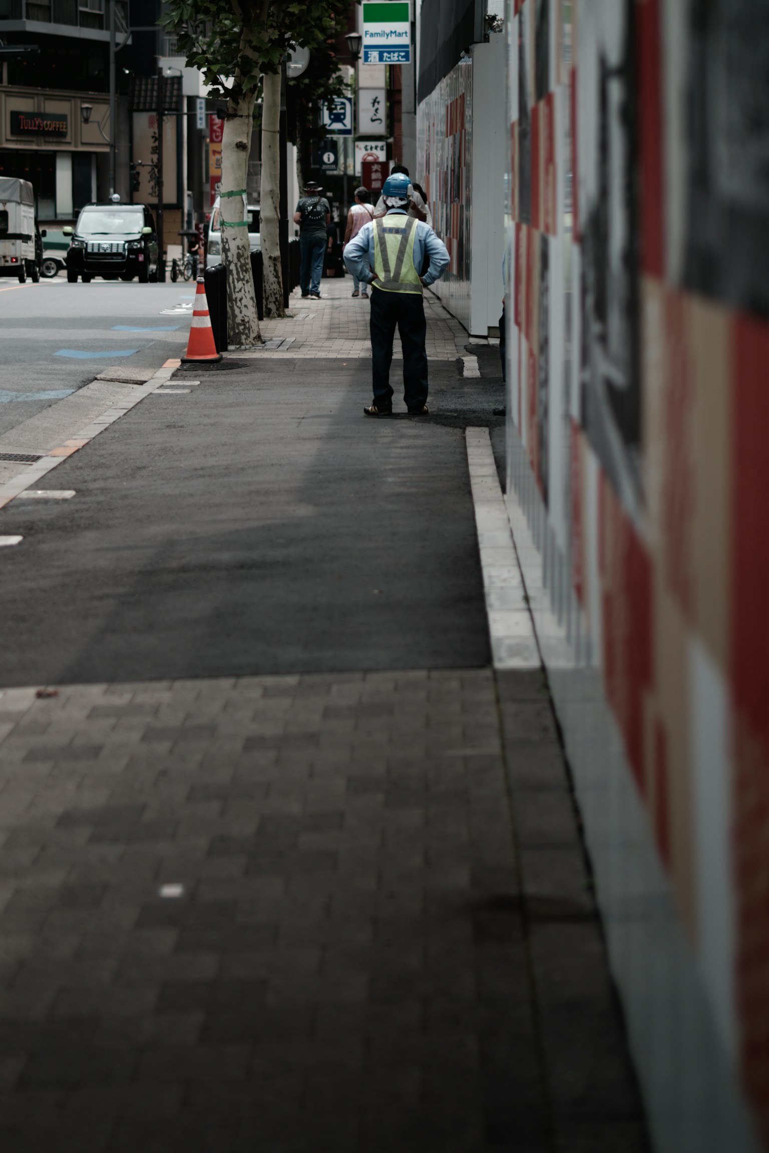 Worker standing on the sidewalk next to a colorful wall