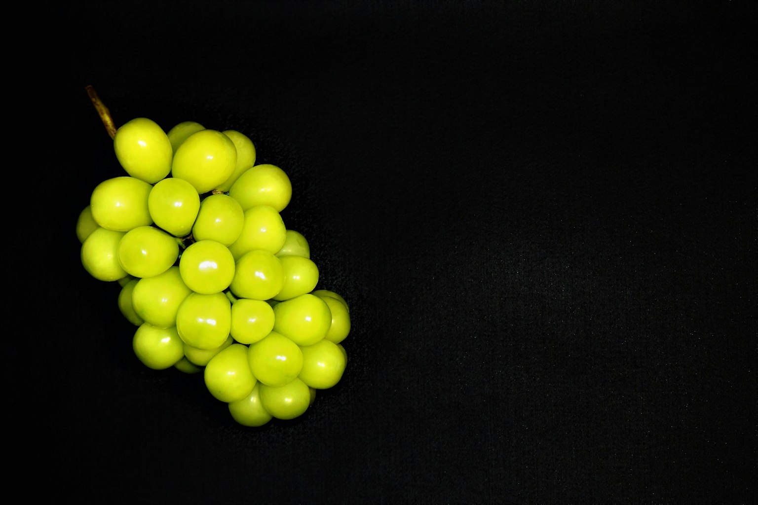 Un grappolo di uva verde su uno sfondo nero