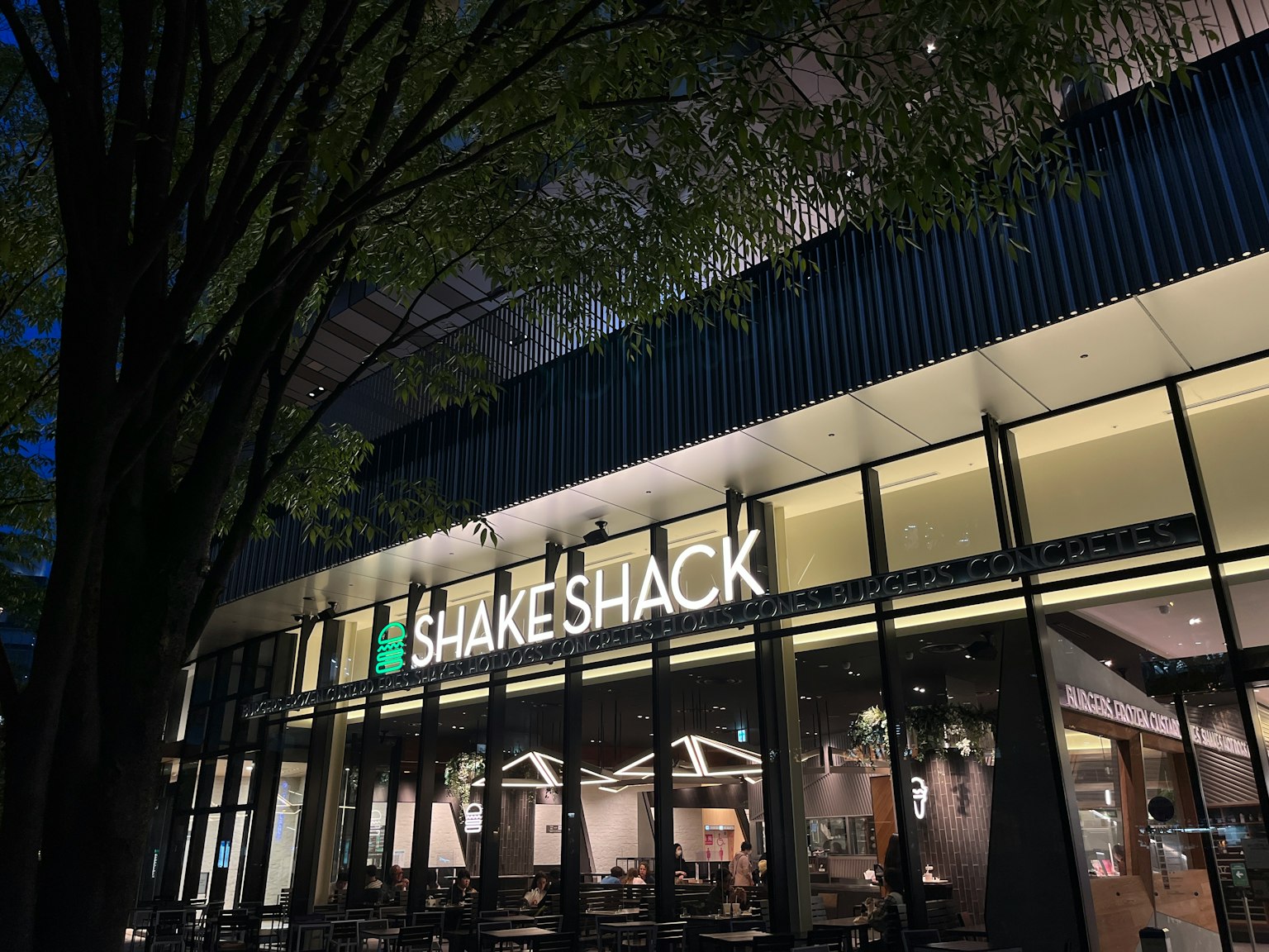ภายนอก Shake Shack ในเวลากลางคืนพร้อมป้ายที่สว่าง