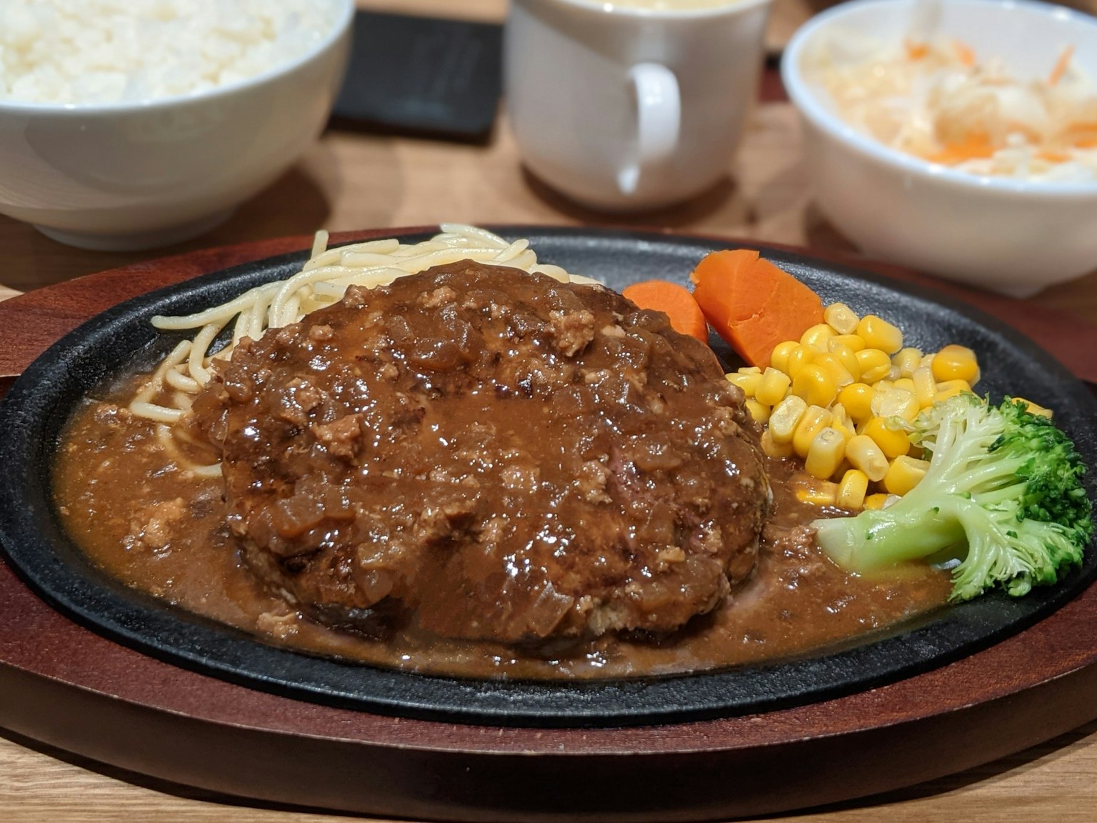 Zischendes Hamburgersteak serviert mit Gemüse und Sauce