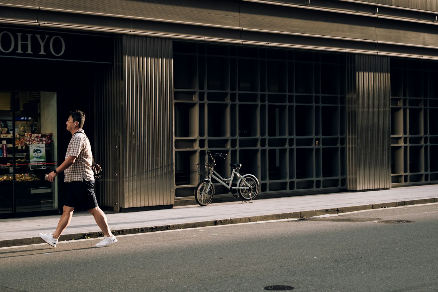 거리를 걷고 있는 남성과 건물 옆에 주차된 자전거