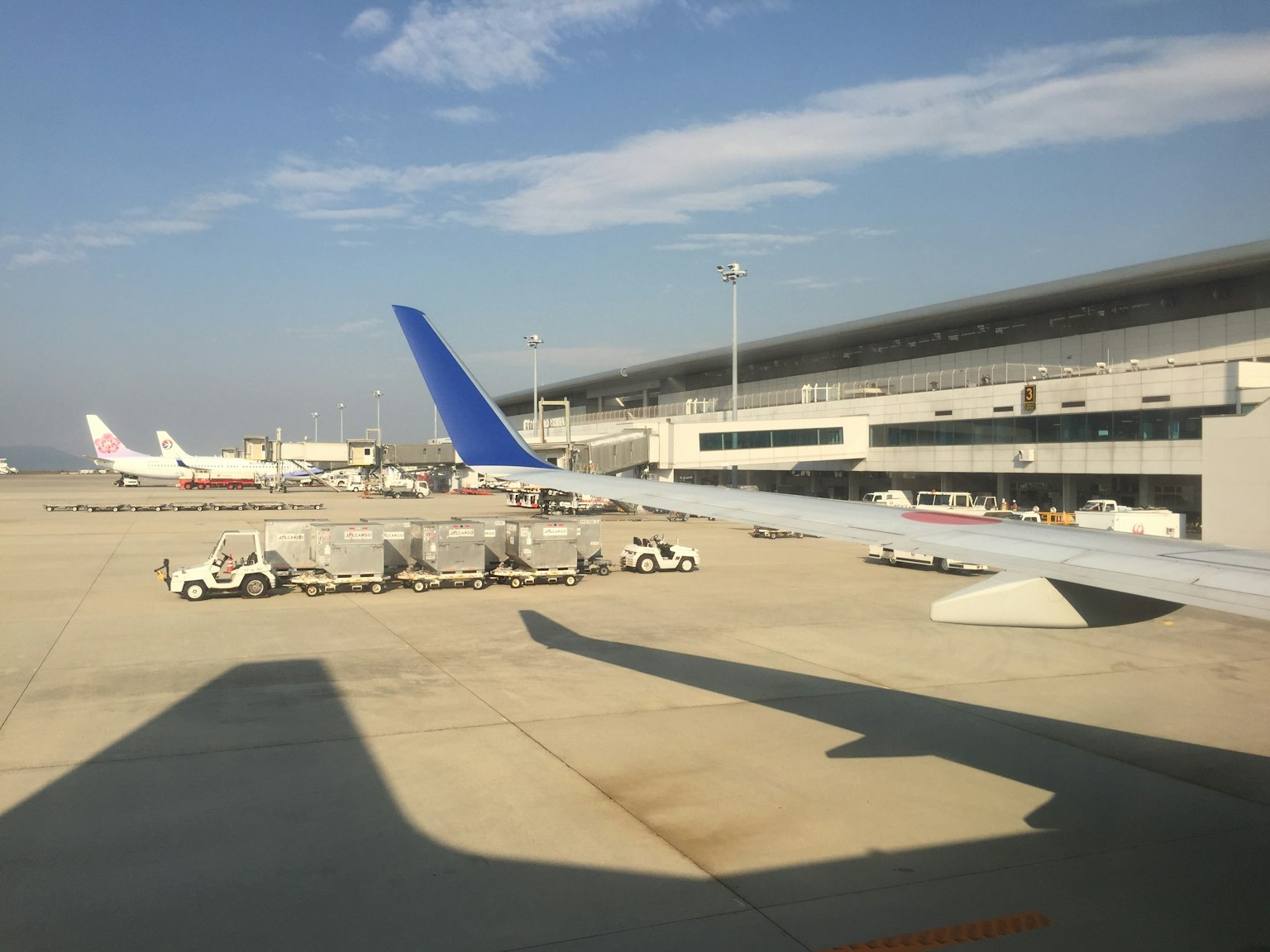 View of an airport runway and terminal with airplanes and ground service vehicles