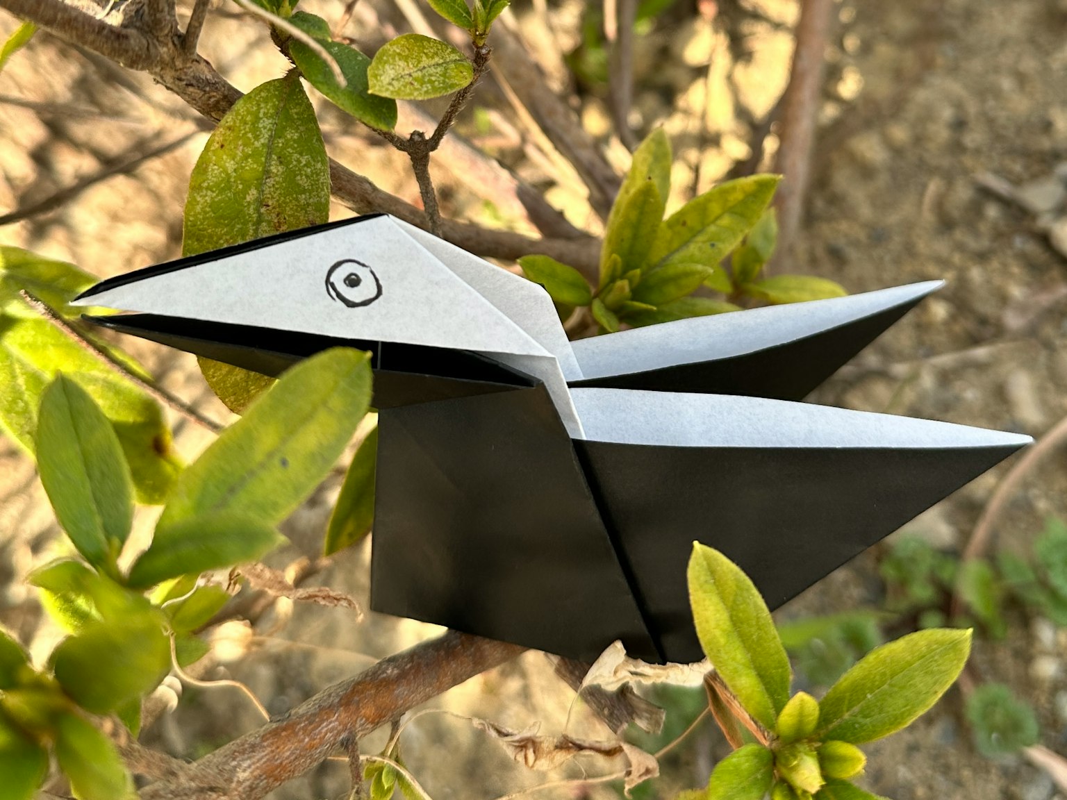 Một con chim origami đen trắng đậu trên lá xanh