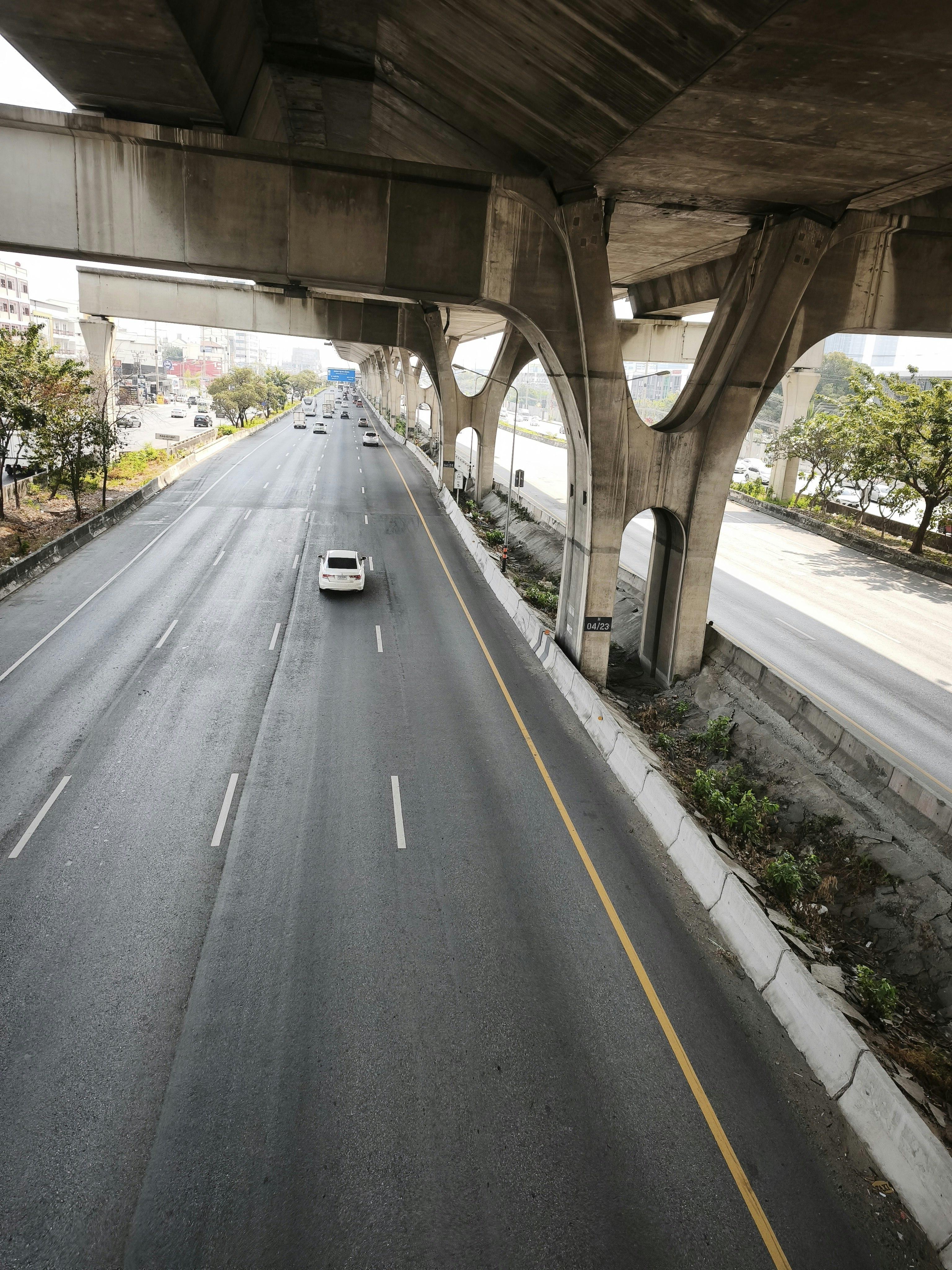 高架下の車道を走る車と歩道