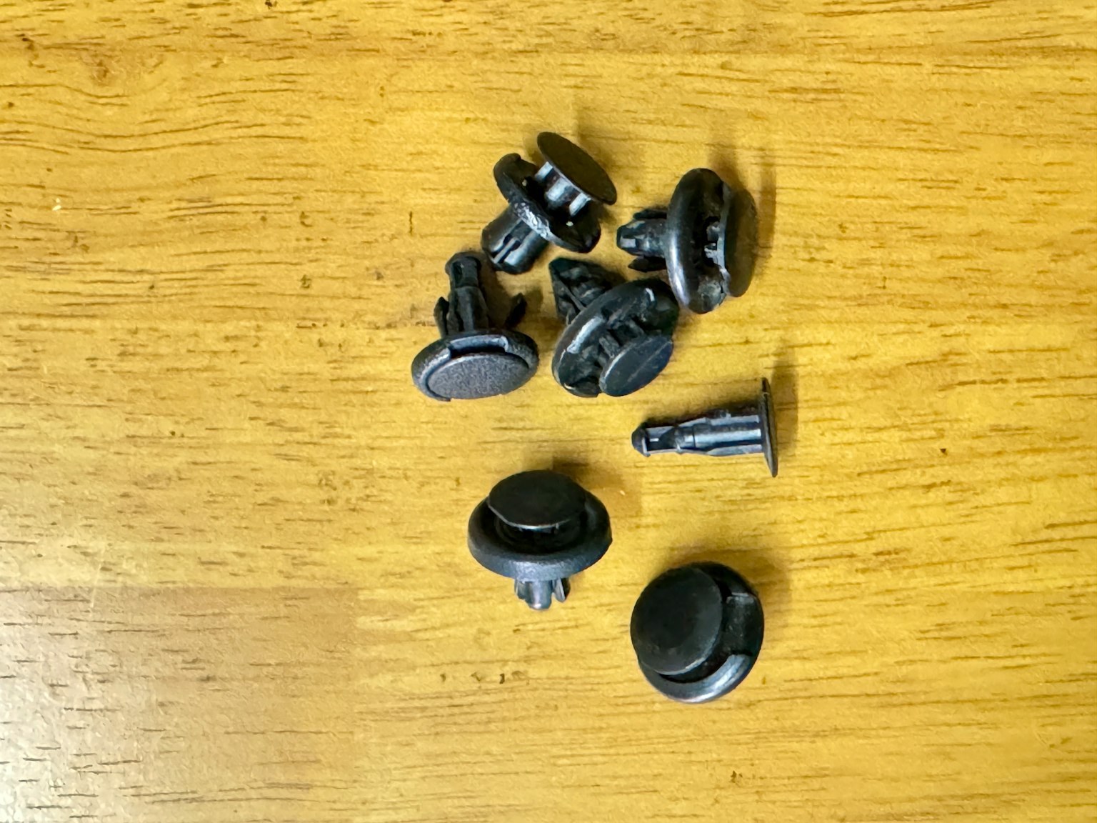 Verschiedene schwarze Knöpfe und Clips auf einem Holztisch verstreut