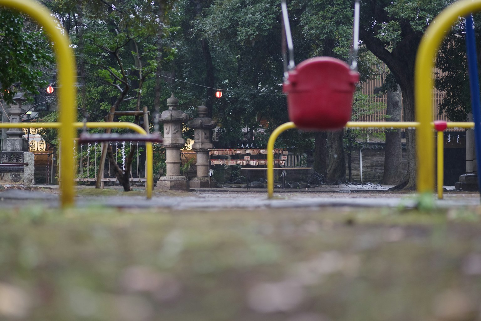 一個遊樂場場景，紅色秋千和黃色欄杆