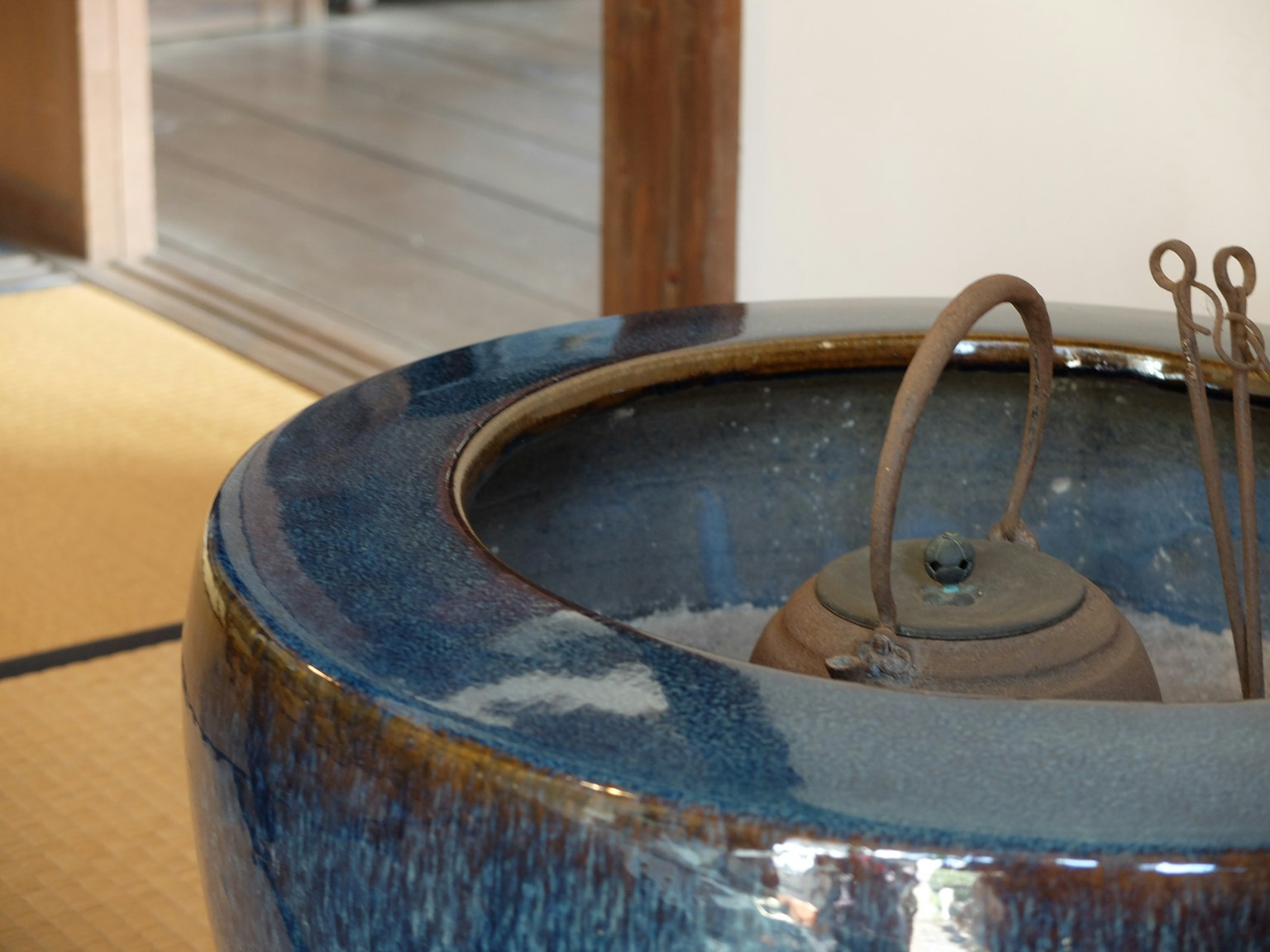Irori en céramique bleue avec des ustensiles en fer dans une pièce japonaise traditionnelle
