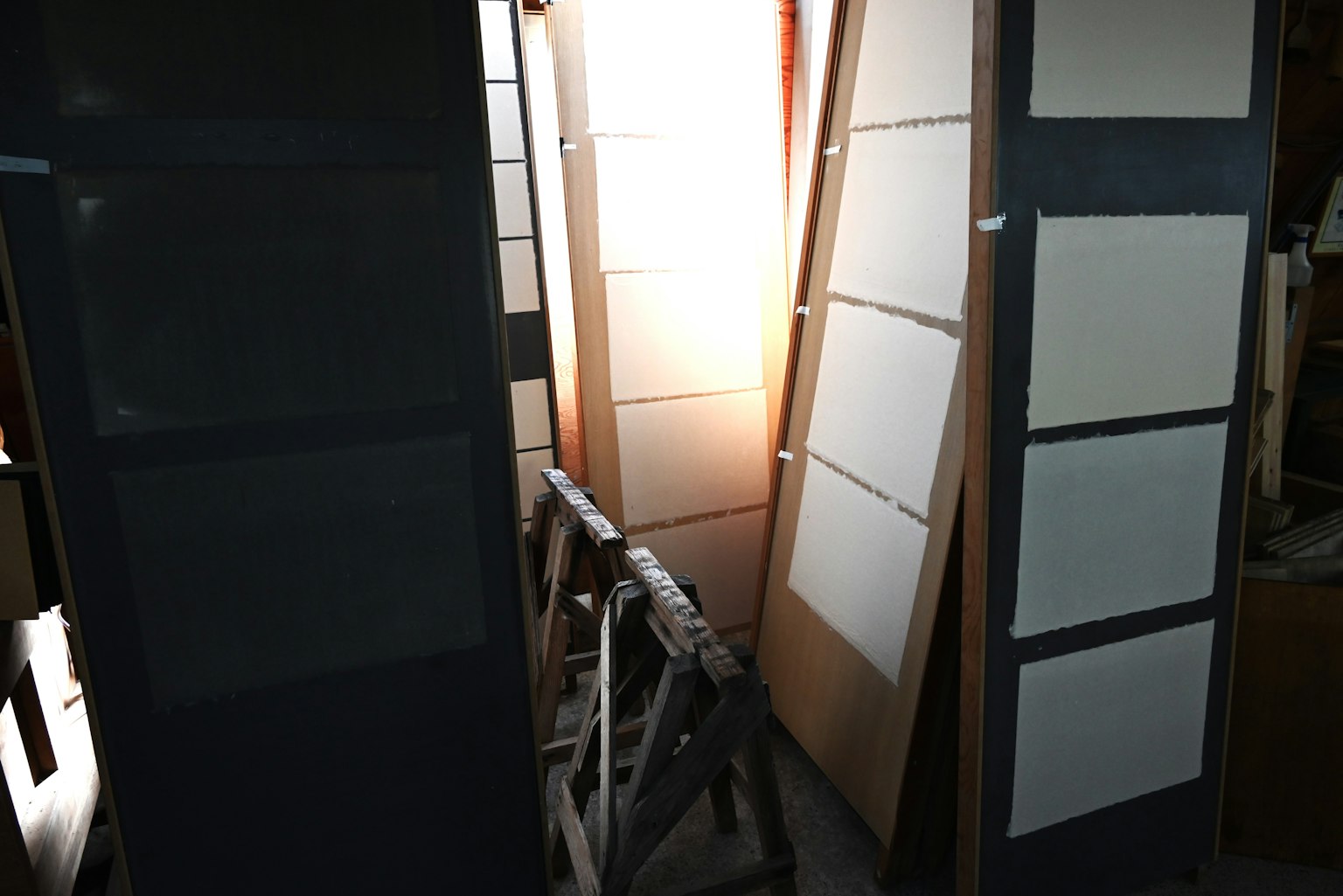 一个室内工作空间，白色板靠在黑色框架上，被明亮的光照亮