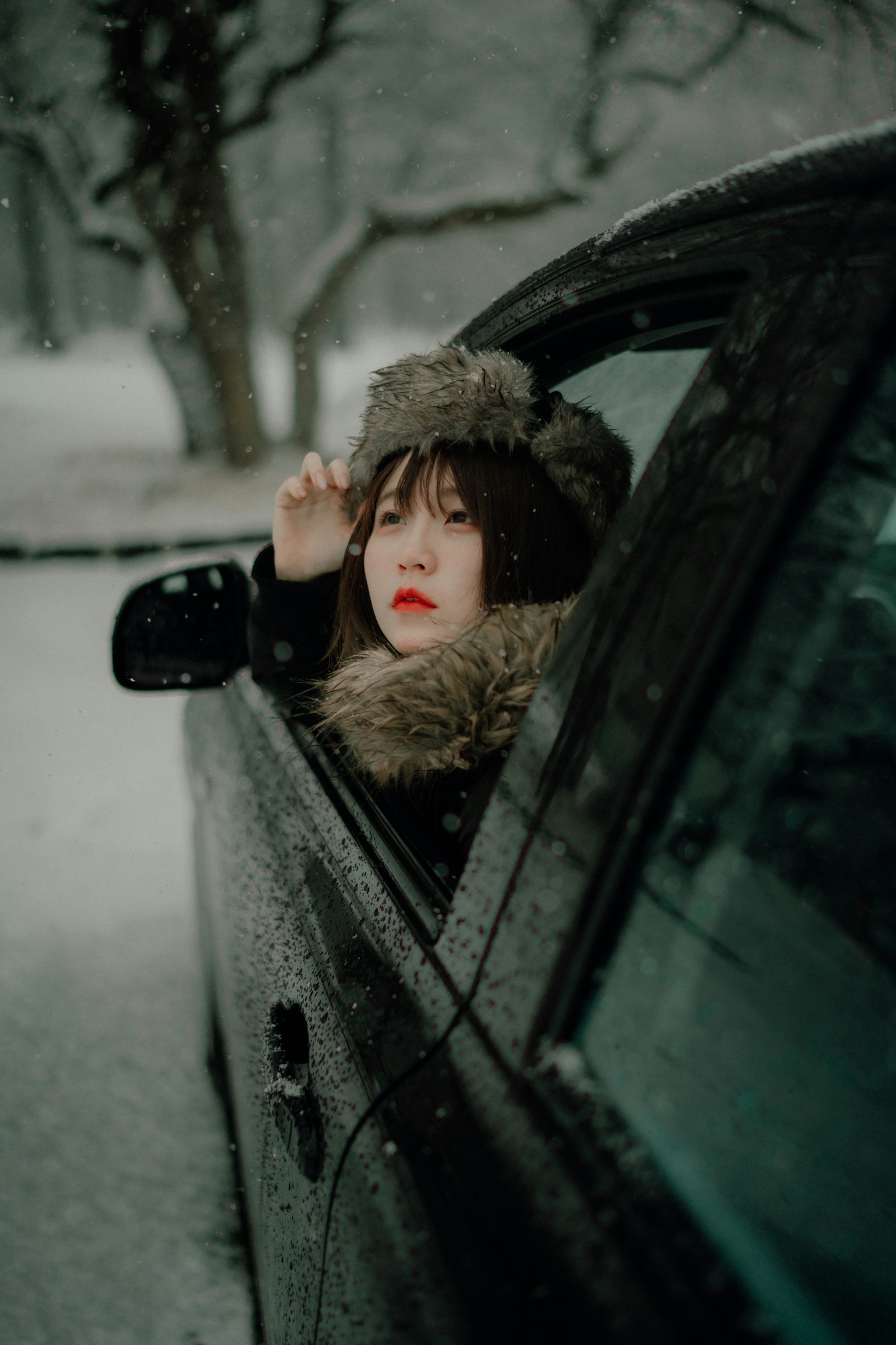 Una donna con le labbra rosse che guarda fuori da un finestrino di auto nella neve