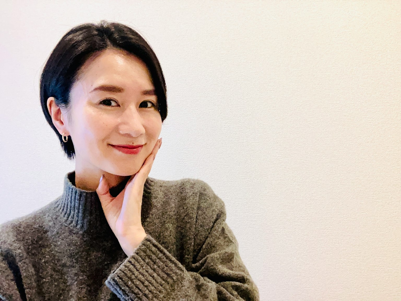 一位短髮女性微笑著用手托著下巴