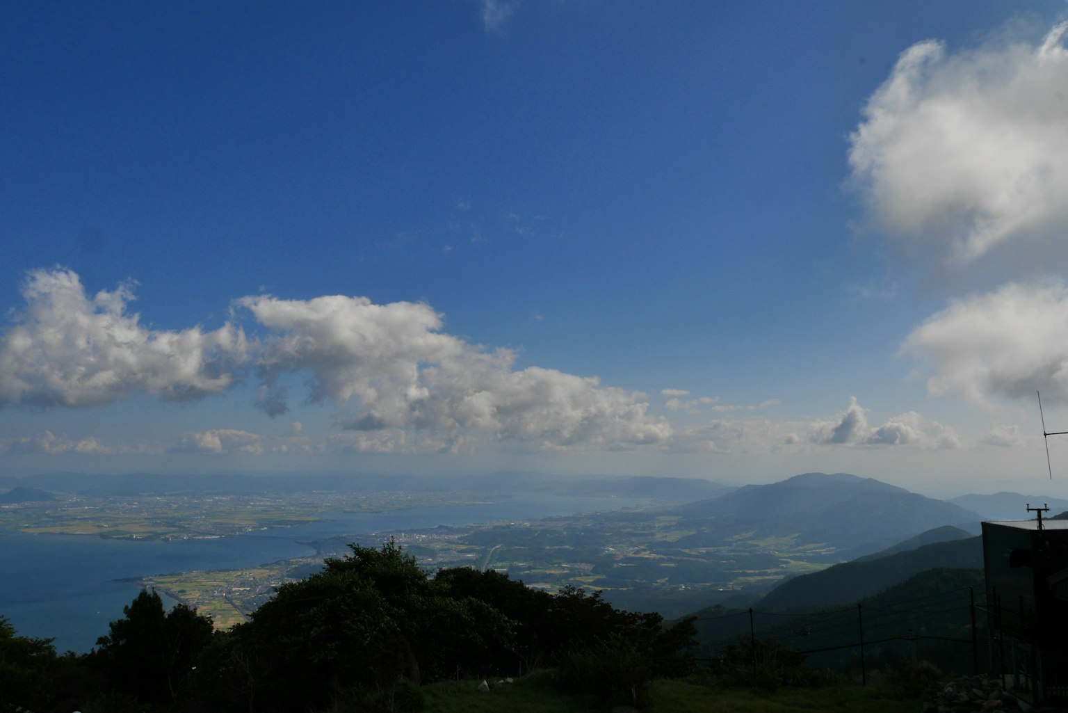 Langit biru luas dengan awan putih yang mengawasi gunung dan laut