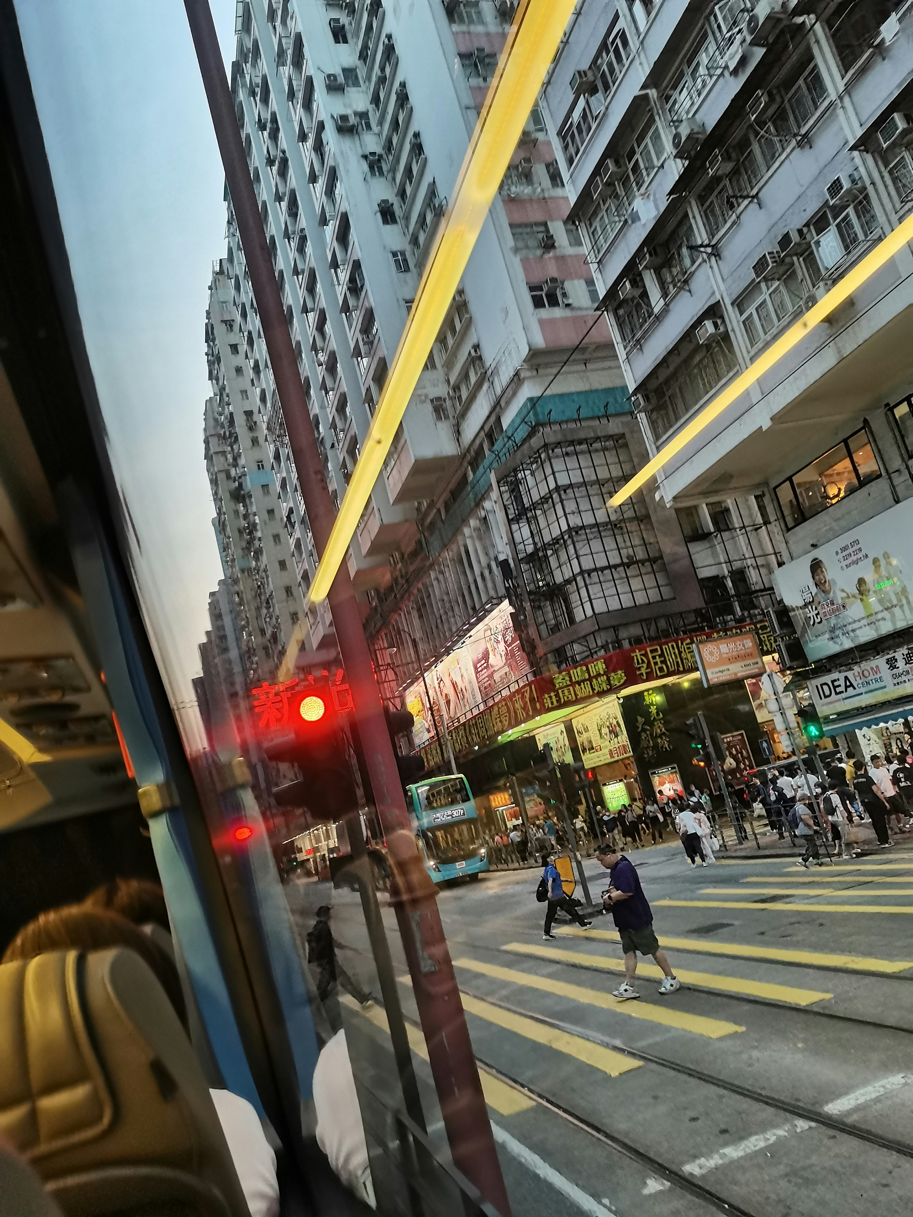 Sommerliche Neon-Reflexionen im Straßenbahnfenster über einer Straße in Hongkong