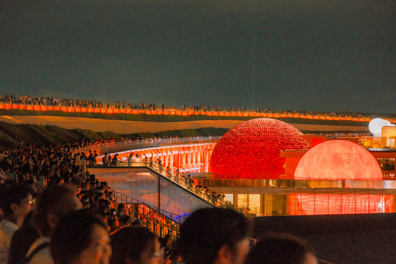 夜のイベントで赤い球体と観客が見える風景
