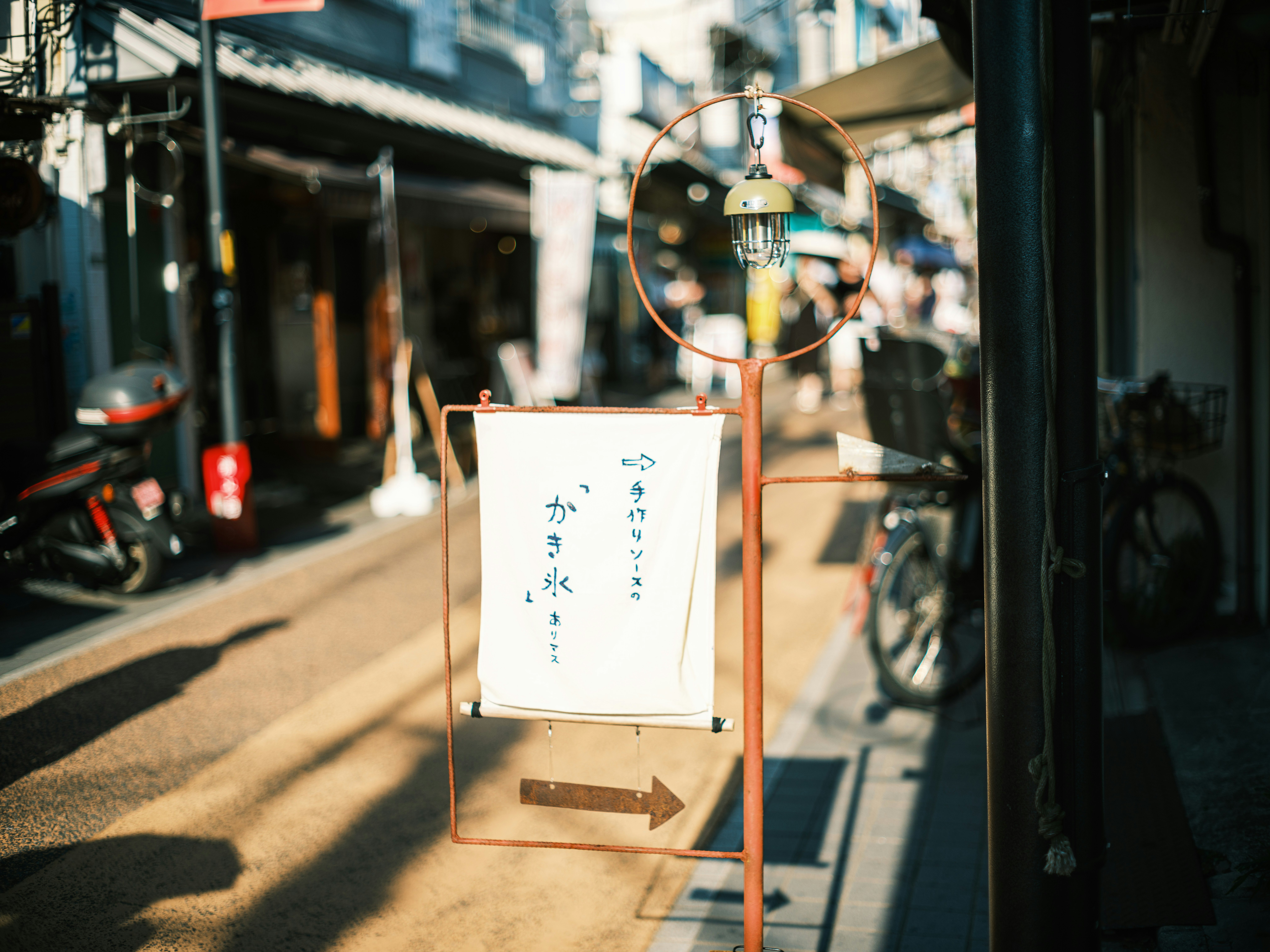 路地の自転車と店先の案内サイン