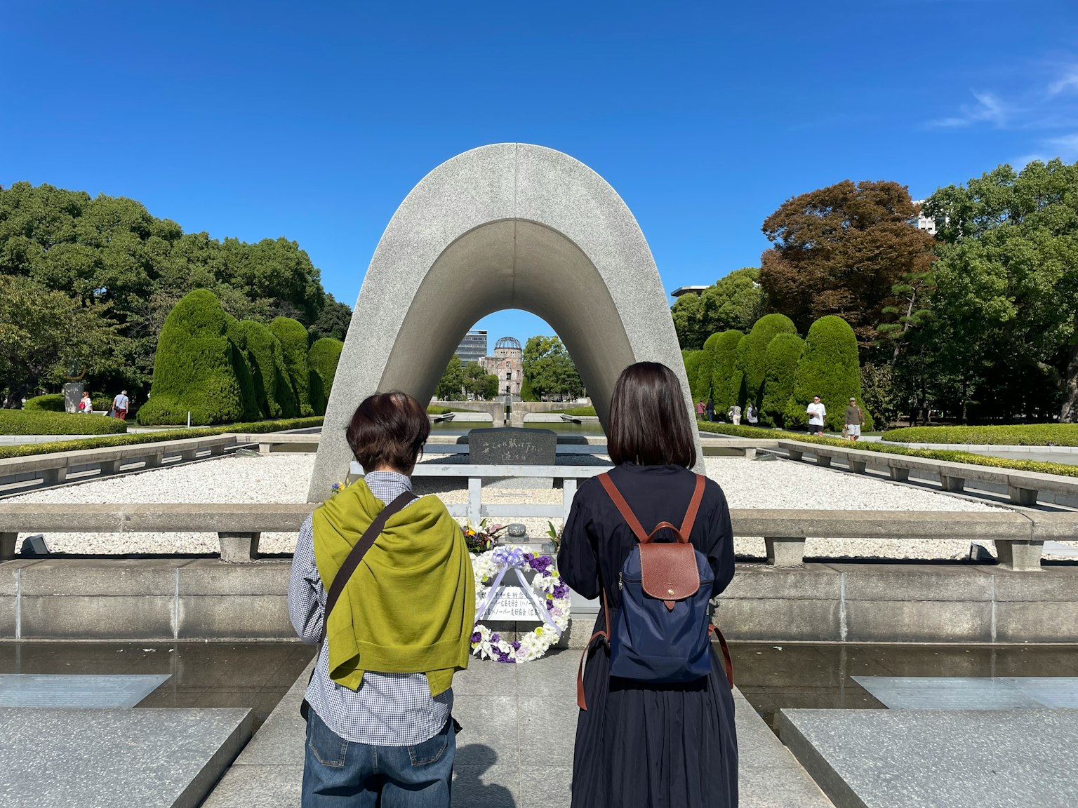 Dos personas mirando a un monumento en forma de arco en un parque