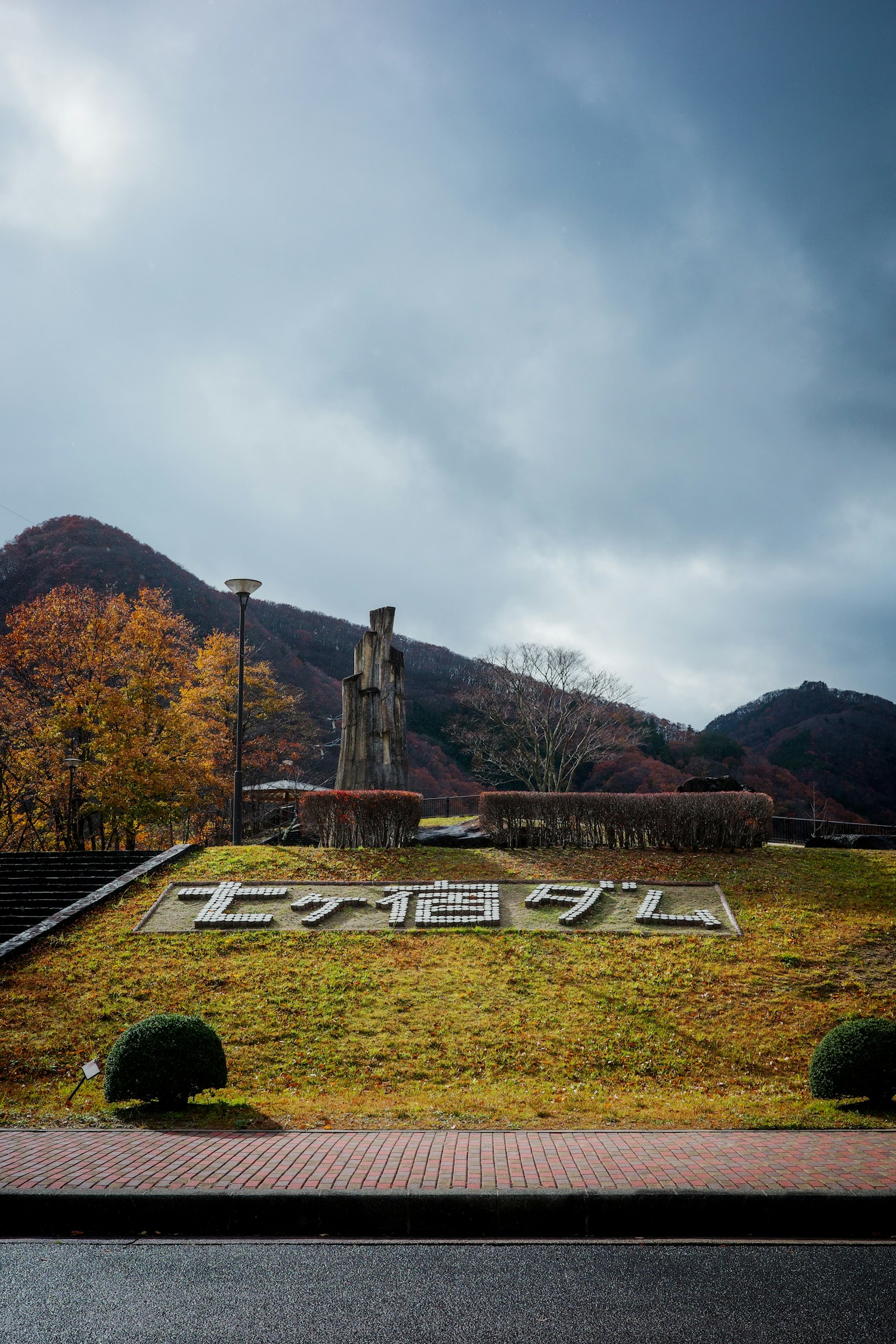 Großes Schild am Eingang eines Parks, umgeben von Bergen und herbstlicher Landschaft