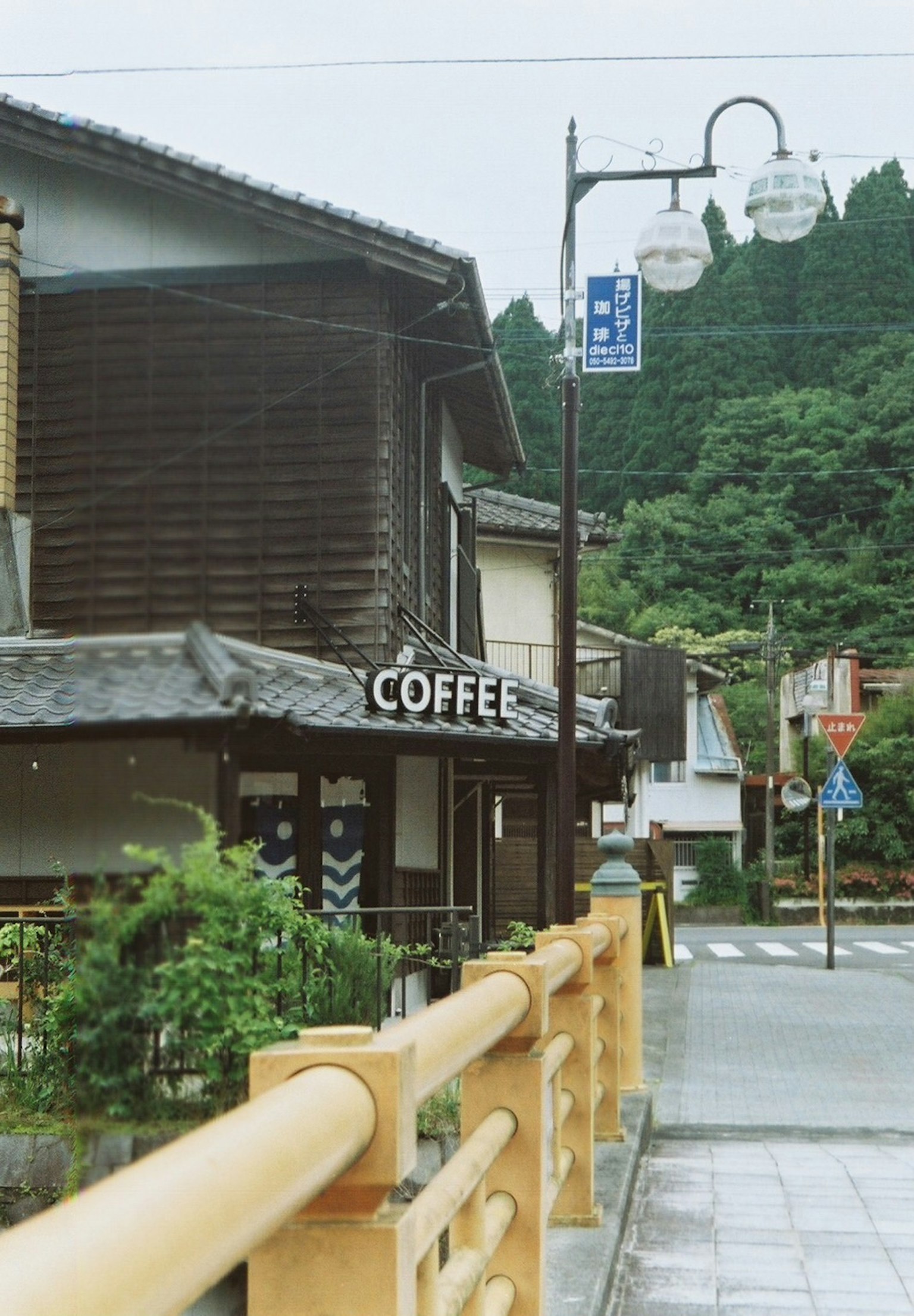 傳統日本小鎮上一家咖啡店的外觀，木質建築和郁郁蔥蔥的背景
