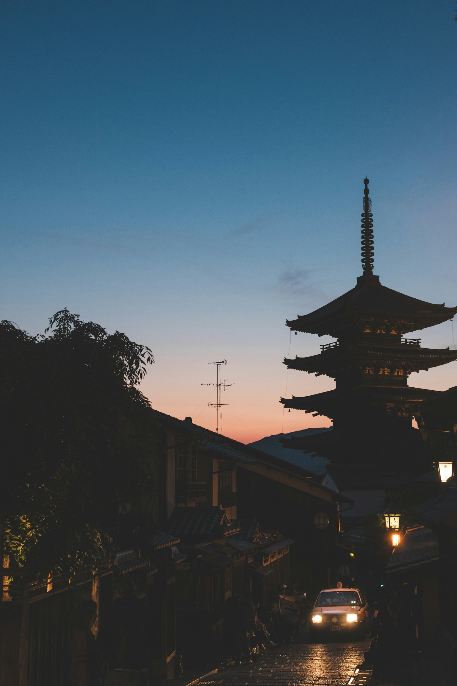 Silueta de una pagoda de cinco pisos contra un cielo al atardecer y calles tranquilas