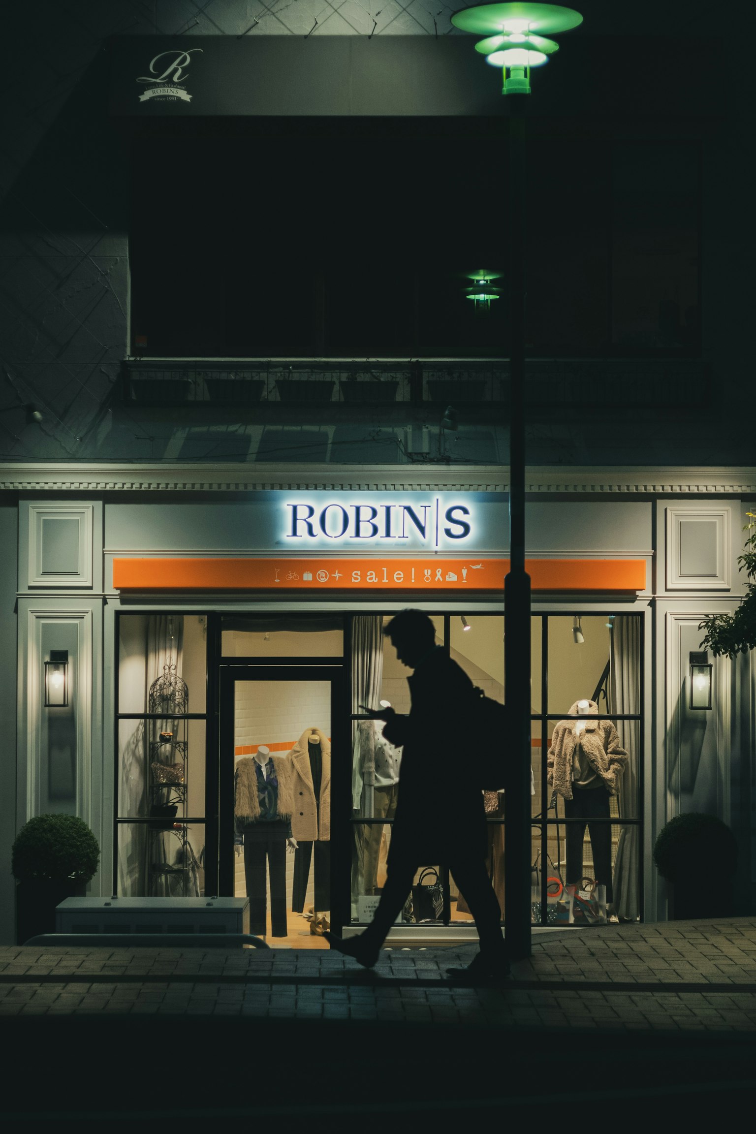 Night scene of Robin's store illuminated with a passerby walking