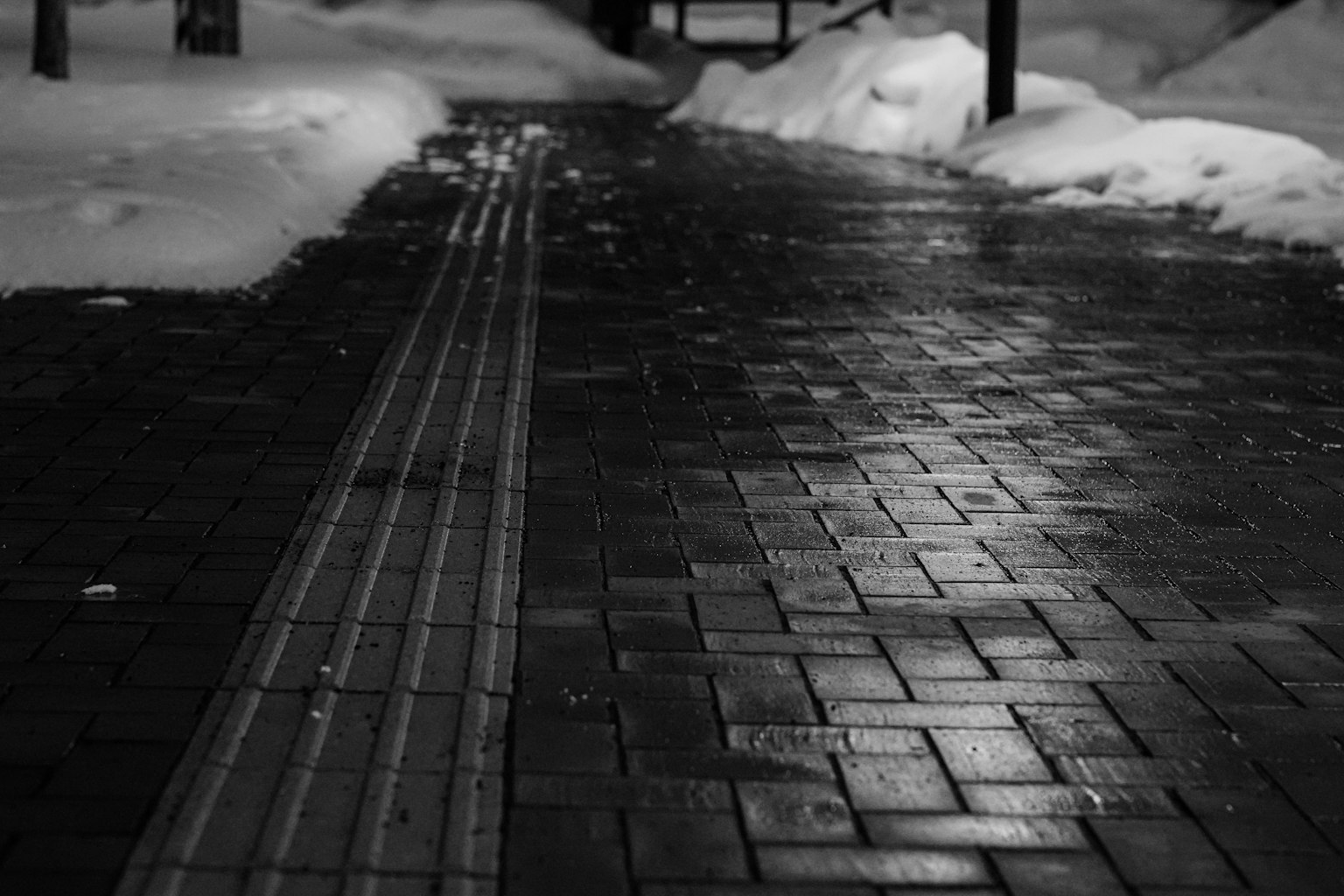 Scène monochrome montrant un chemin enneigé avec des motifs de carreaux mouillés