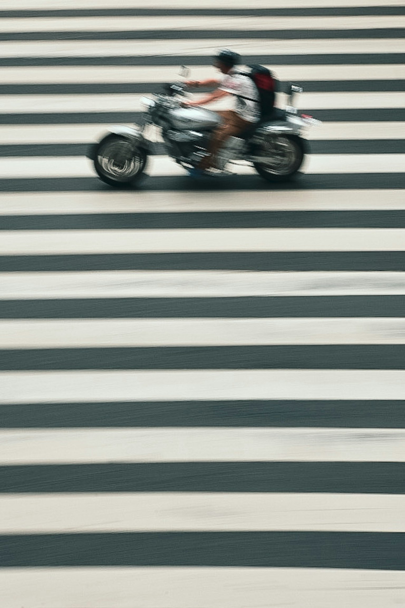Una persona su una motocicletta bianca che attraversa un attraversamento pedonale a strisce