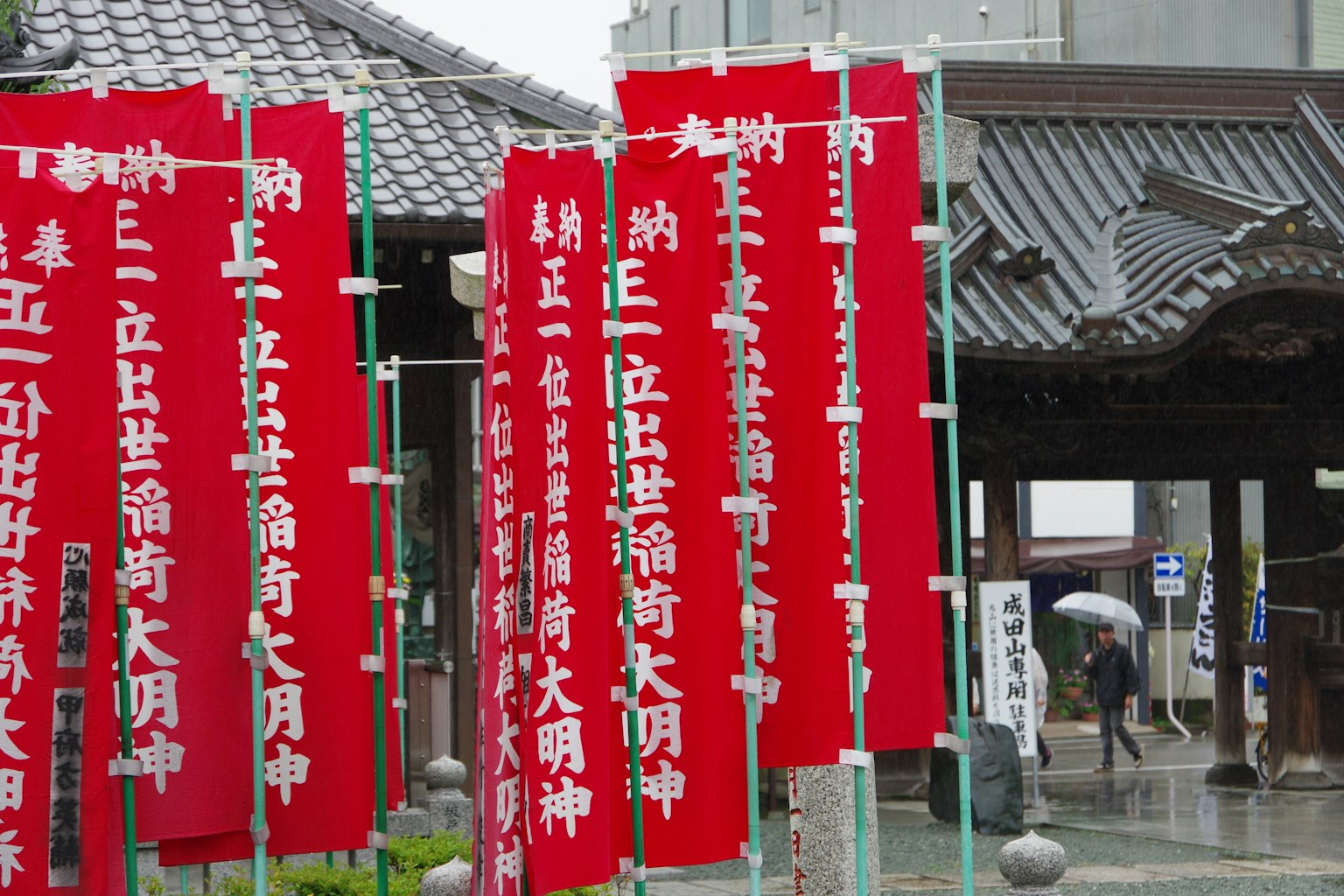 Entrada de un templo con pancartas rojas que exhiben texto japonés