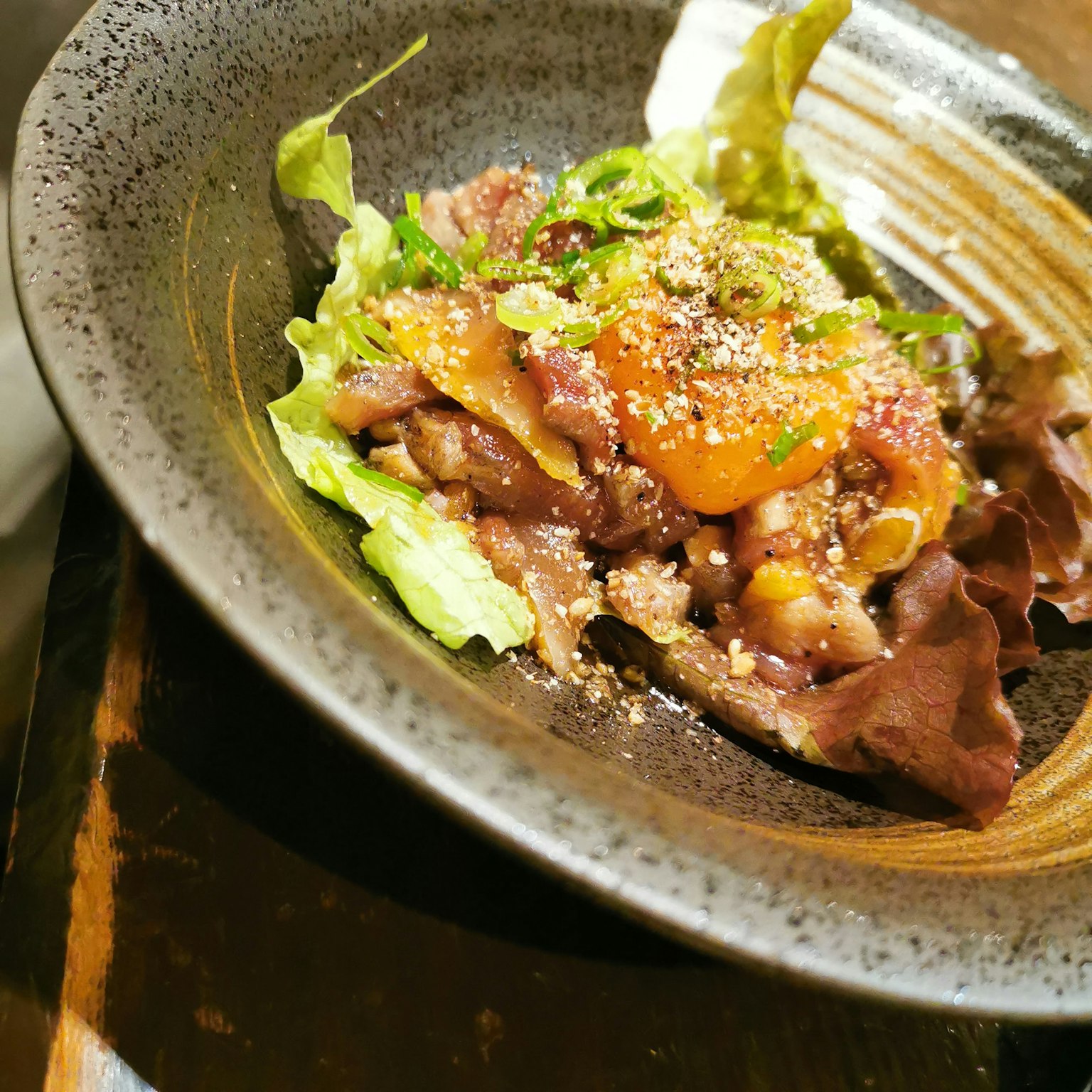 Ensalada de carne y lechuga deliciosa servida en un tazón oscuro