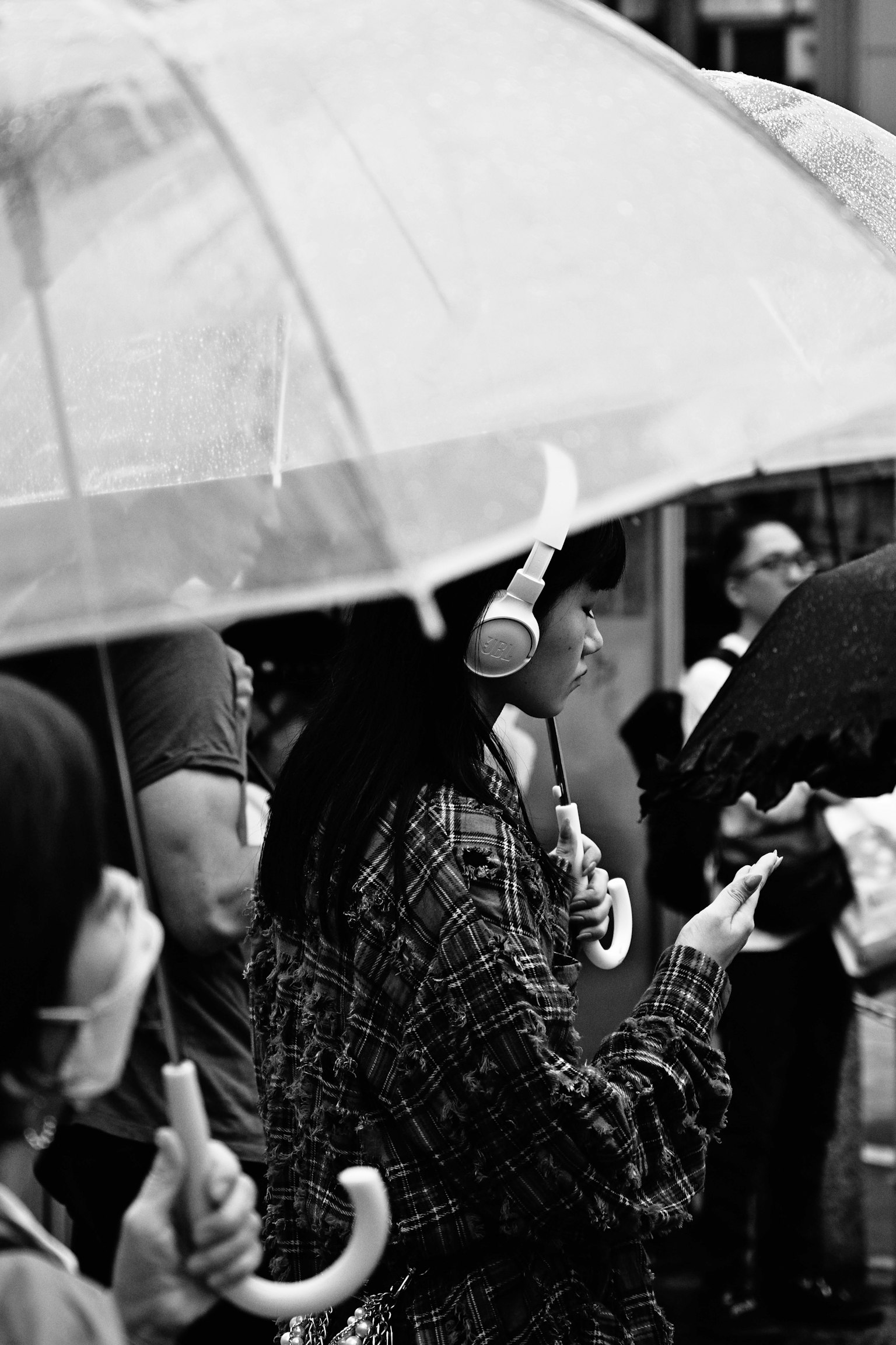 Woman listening to music under an umbrella with people around