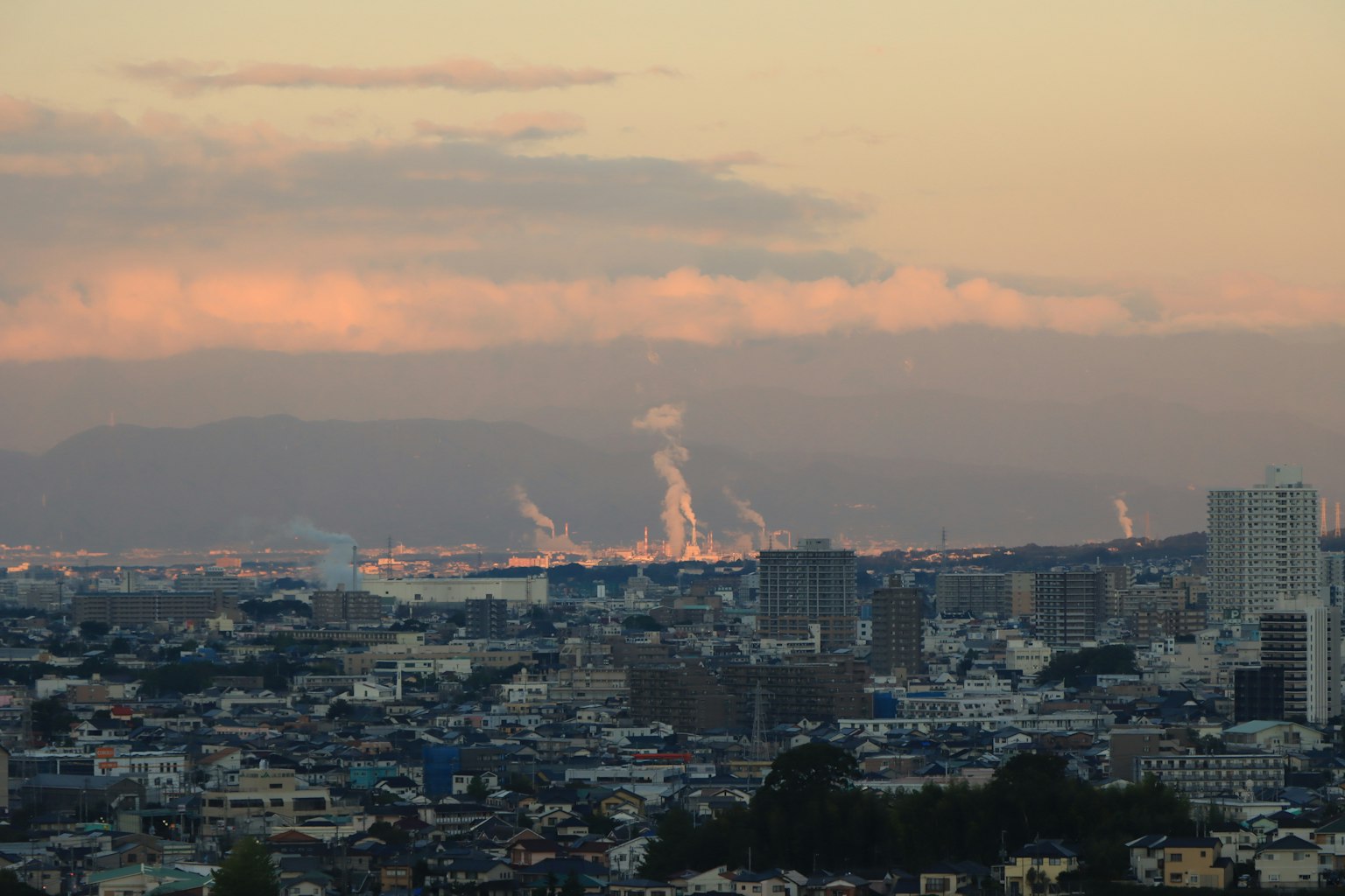 日落时分的城市景观，工厂冒出烟雾