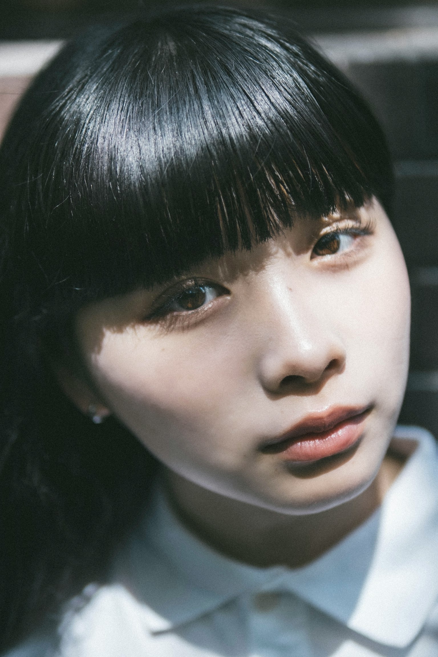 年輕女性的肖像 黑髮和劉海 穿著白色襯衫 背景明亮