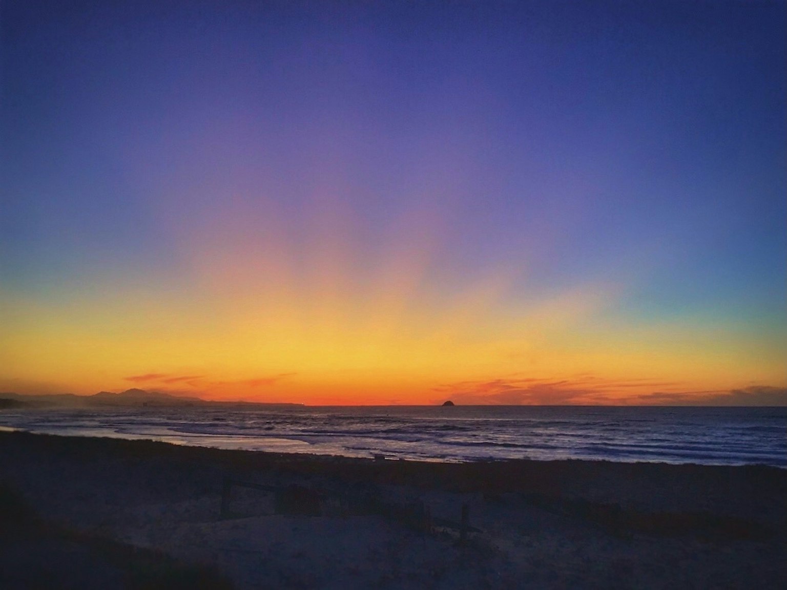 Magnifique coucher de soleil sur l'océan avec des teintes orange et violettes et des vagues douces