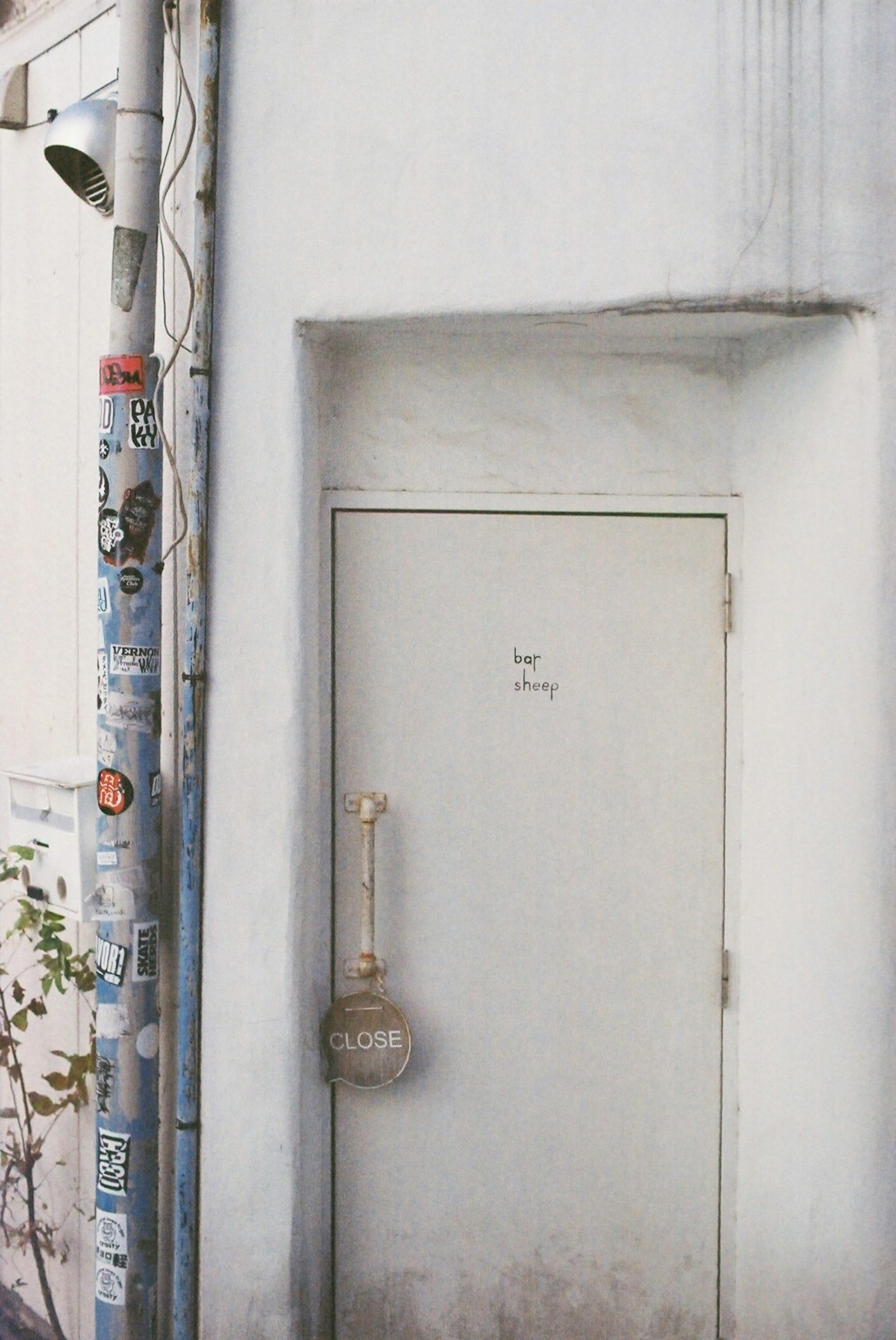 Une porte blanche simple entourée d'un mur blanc et d'un poteau couvert d'autocollants