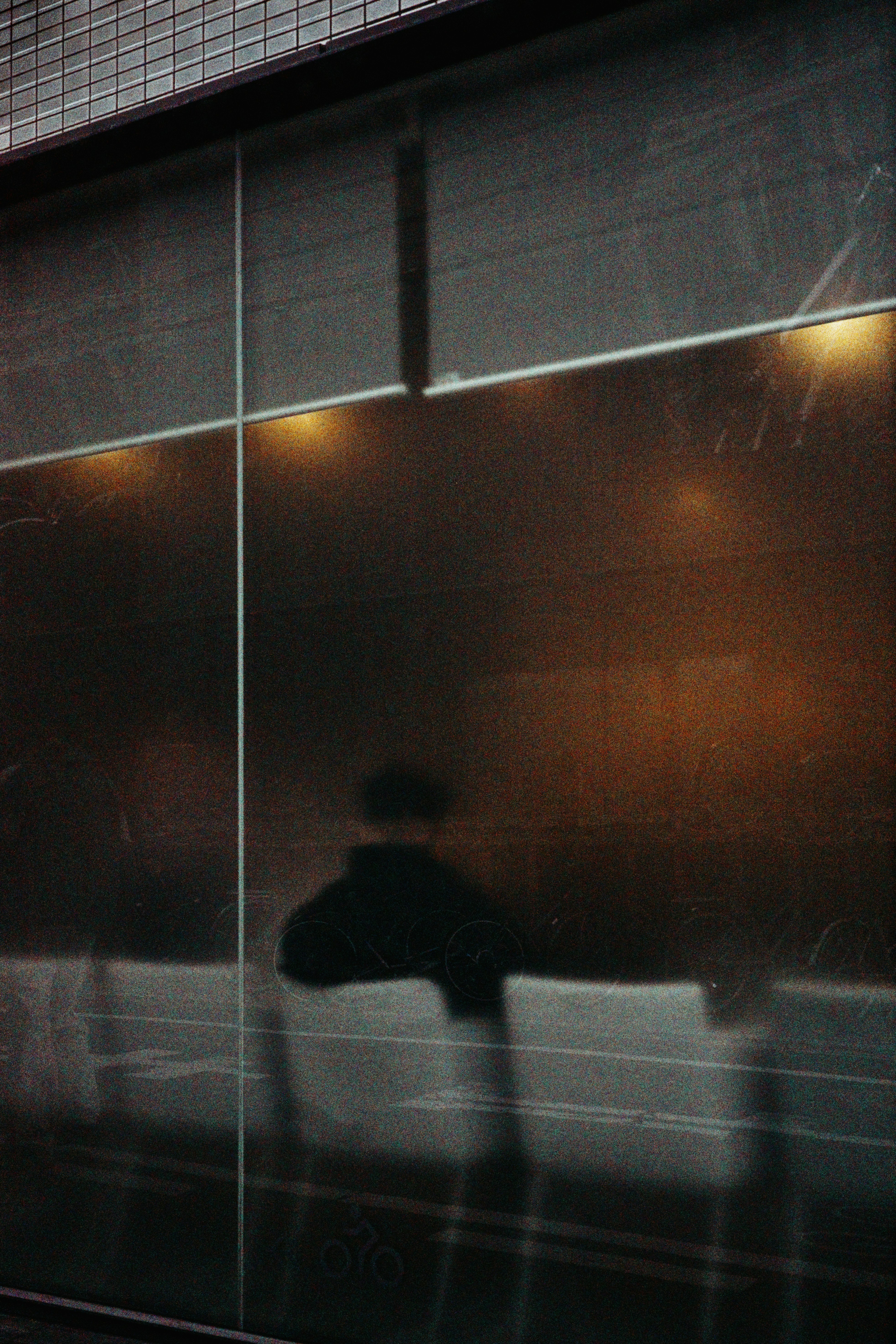 Silhouette of a person behind glass with city lights