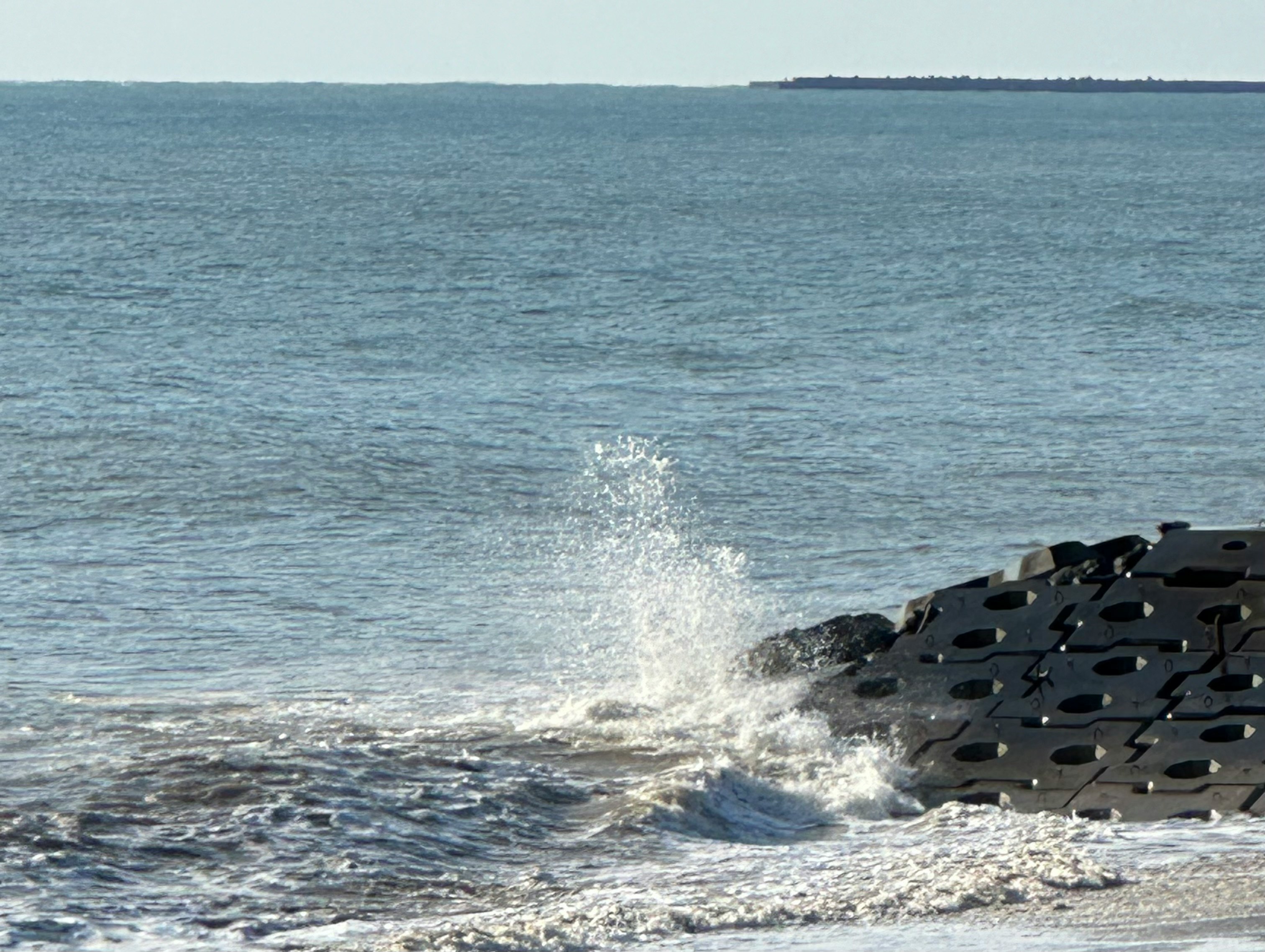 olas rompiendo contra un rompeolas en el mar