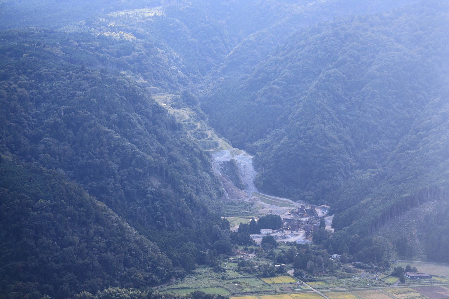 Ein von Bergen umgebenes Tal mit einem kleinen Dorf, das flussabwärts sichtbar ist