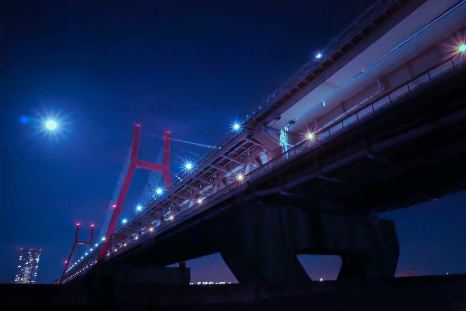 Una scena bellissima di un ponte rosso illuminato di notte contro un cielo blu