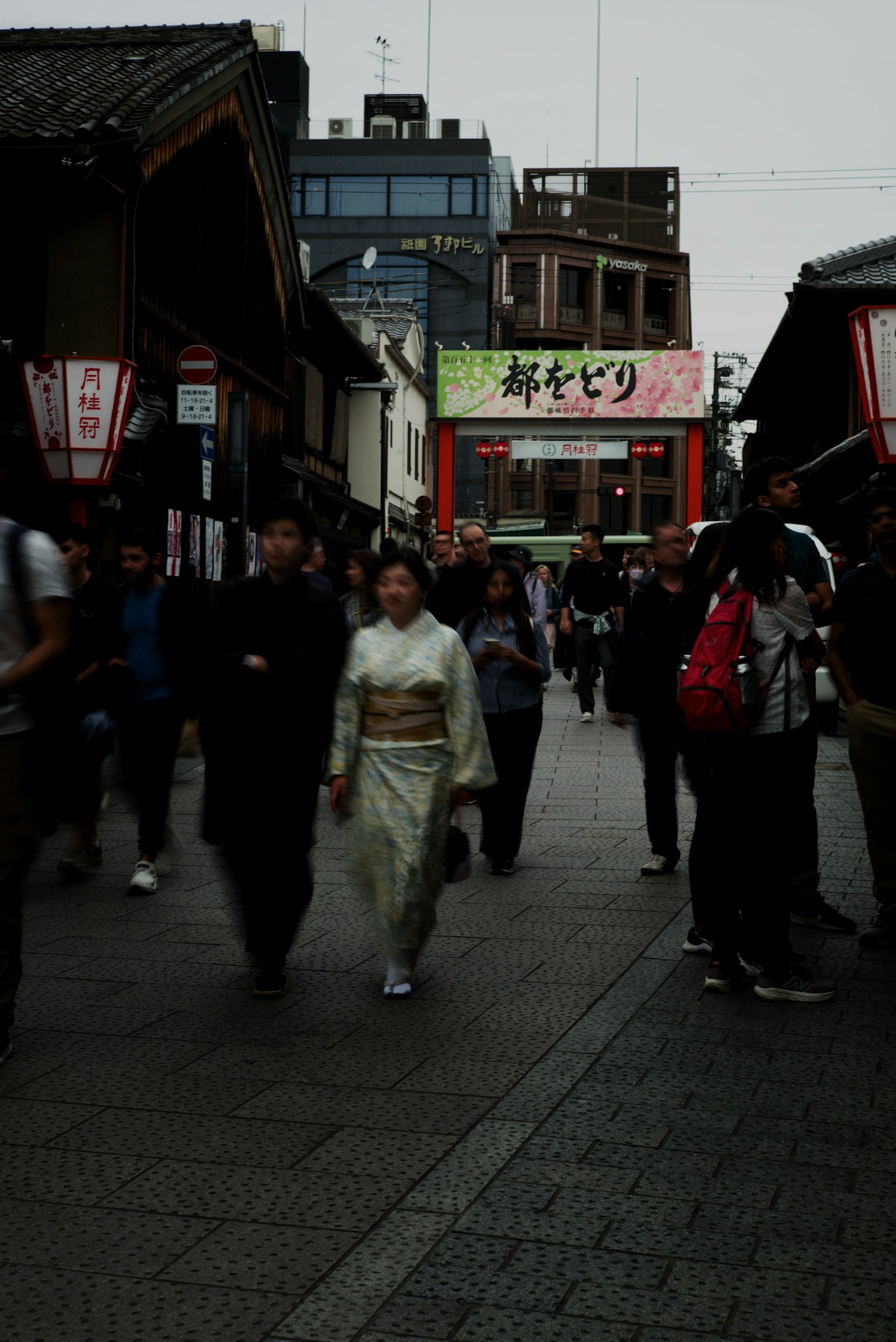 Eine Frau in einem weißen Kimono, die in einer belebten Straße zwischen einer Menschenmenge geht