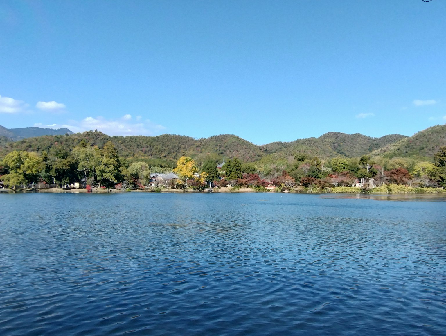 Pemandangan danau biru yang dikelilingi bukit dan pepohonan