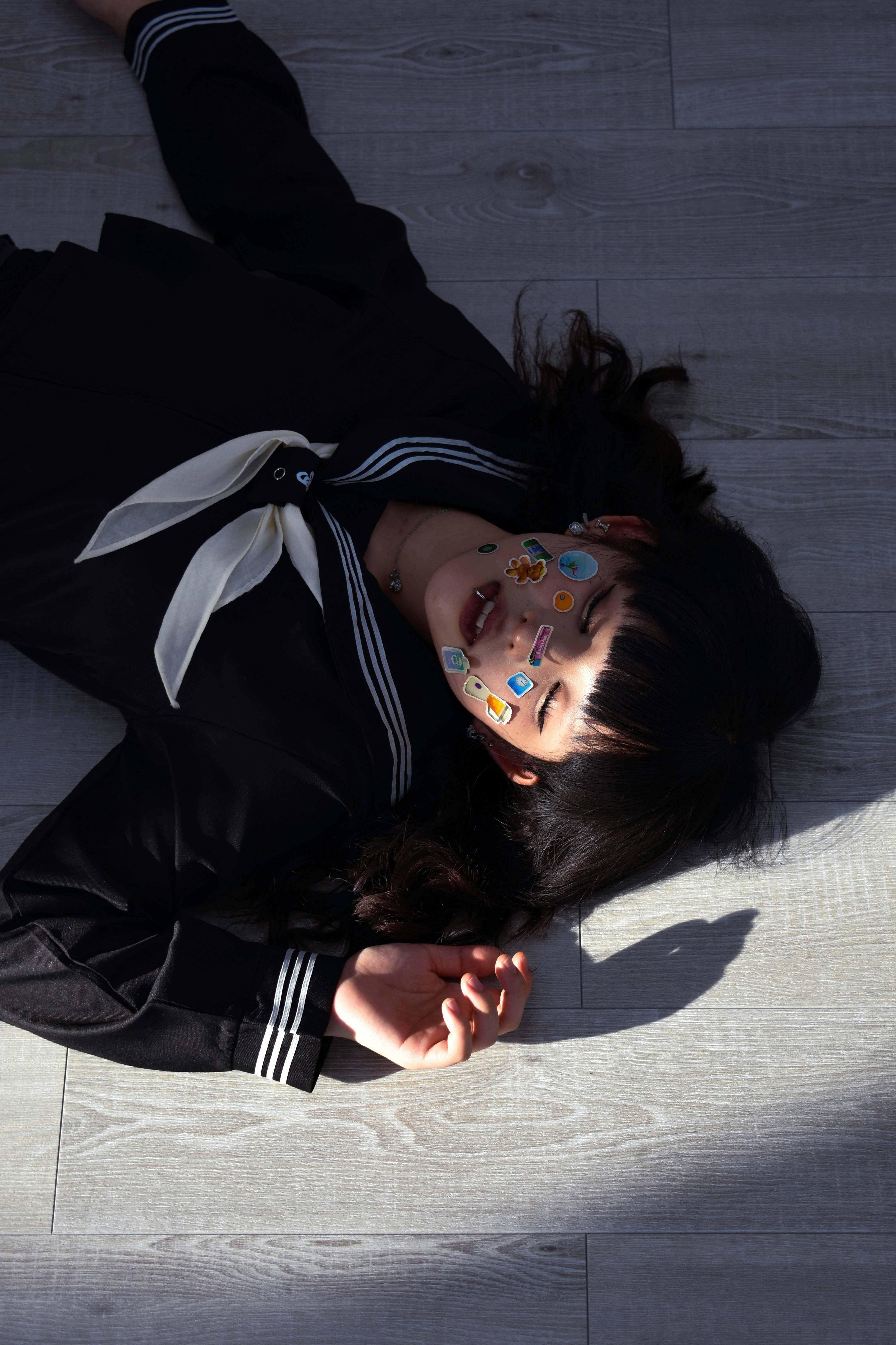 黒い制服風の衣装を着た人物の横たわるポートレート