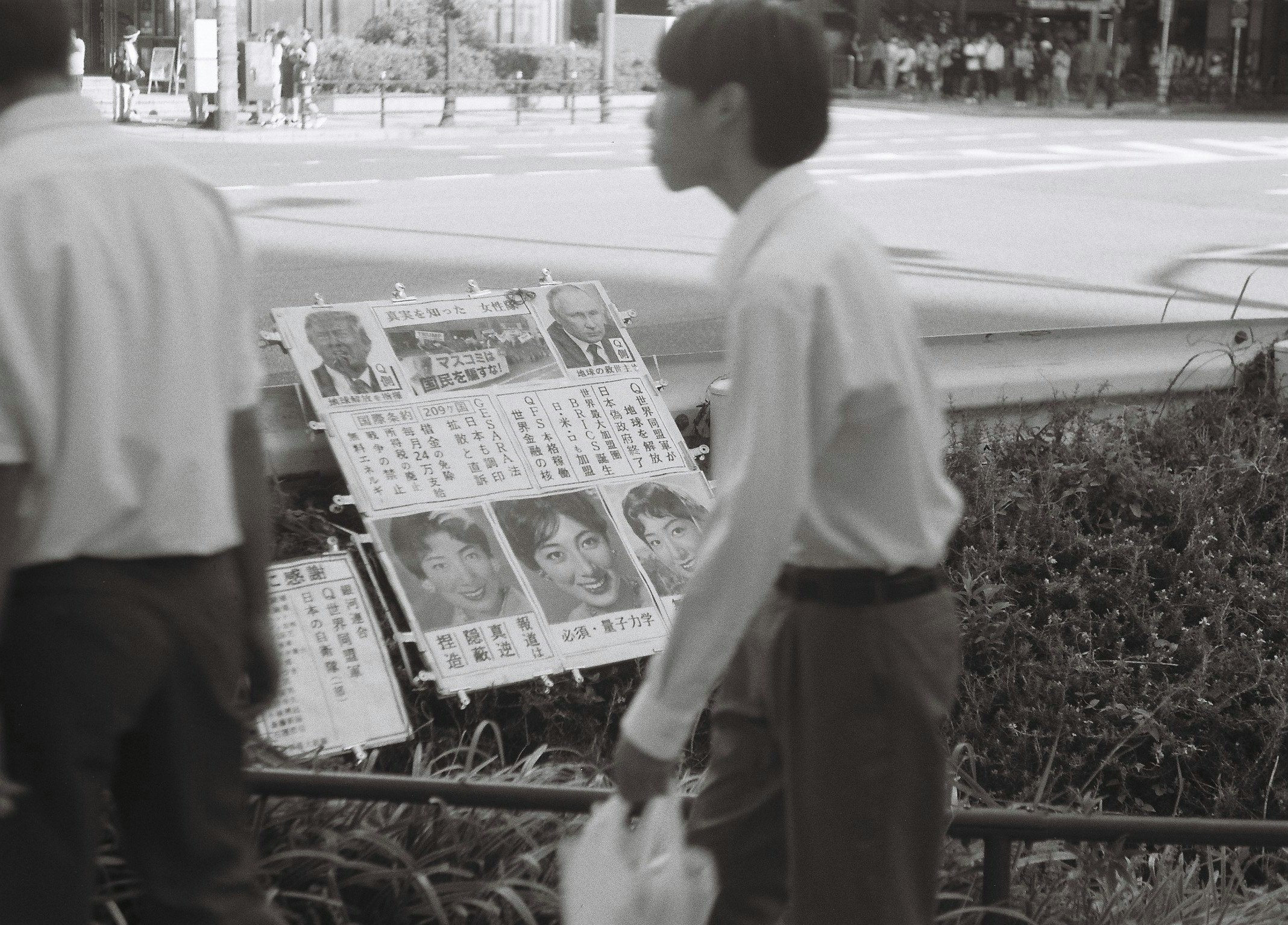 新聞を持つ人が並ぶ街角のベンチ前