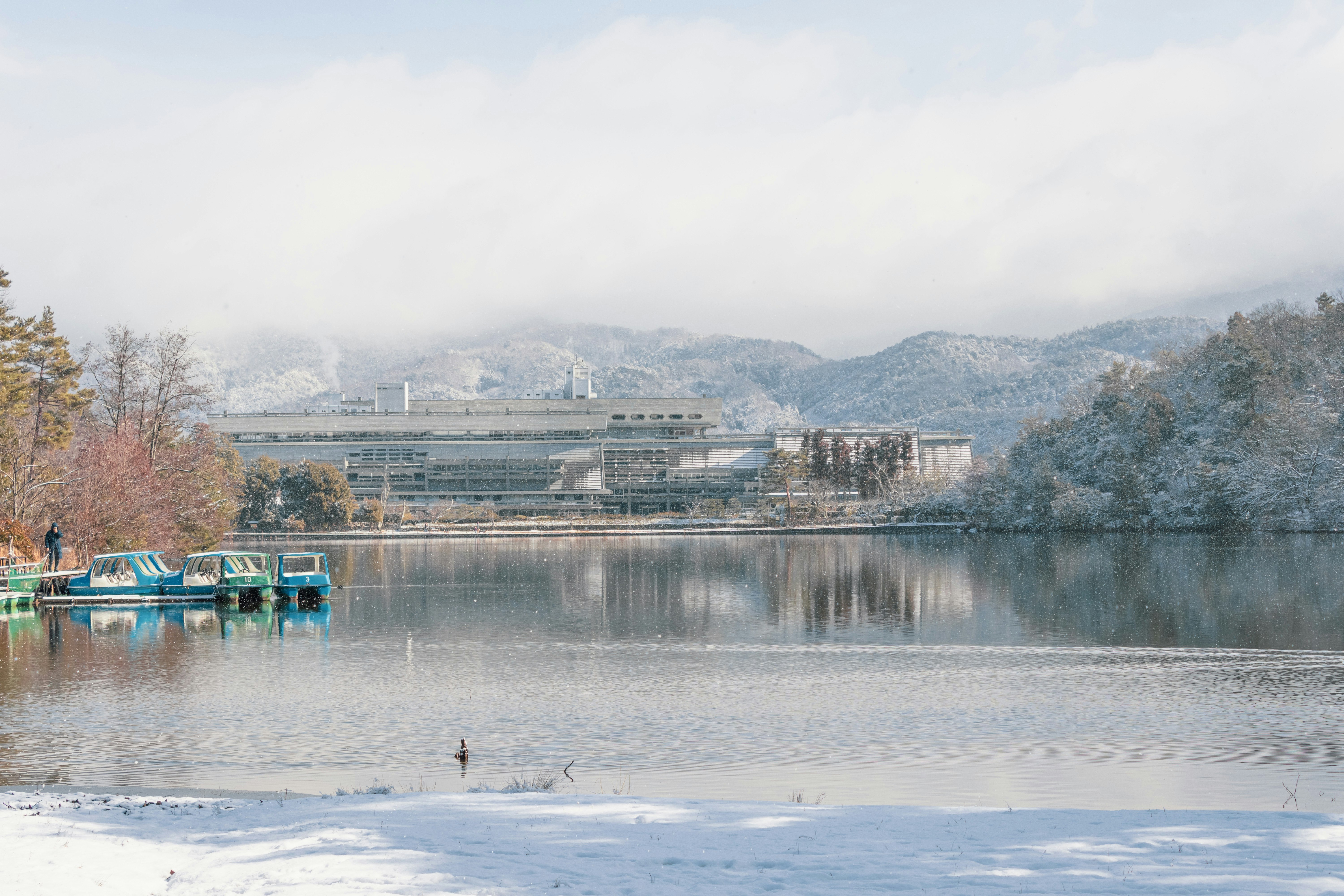 白雪覆盖的湖边停着船只与远处群山