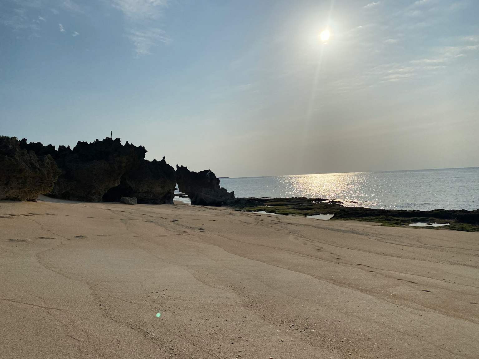 Vue panoramique d'une plage avec mer calme et formations rocheuses