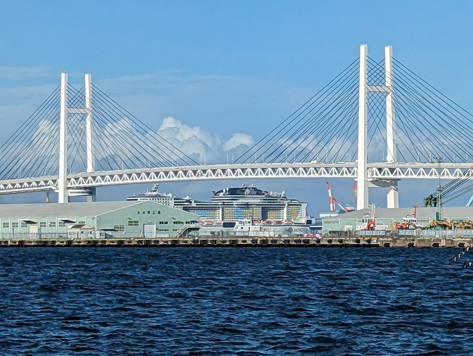 Ponte di Yokohama che si estende sulle acque blu con edifici portuali
