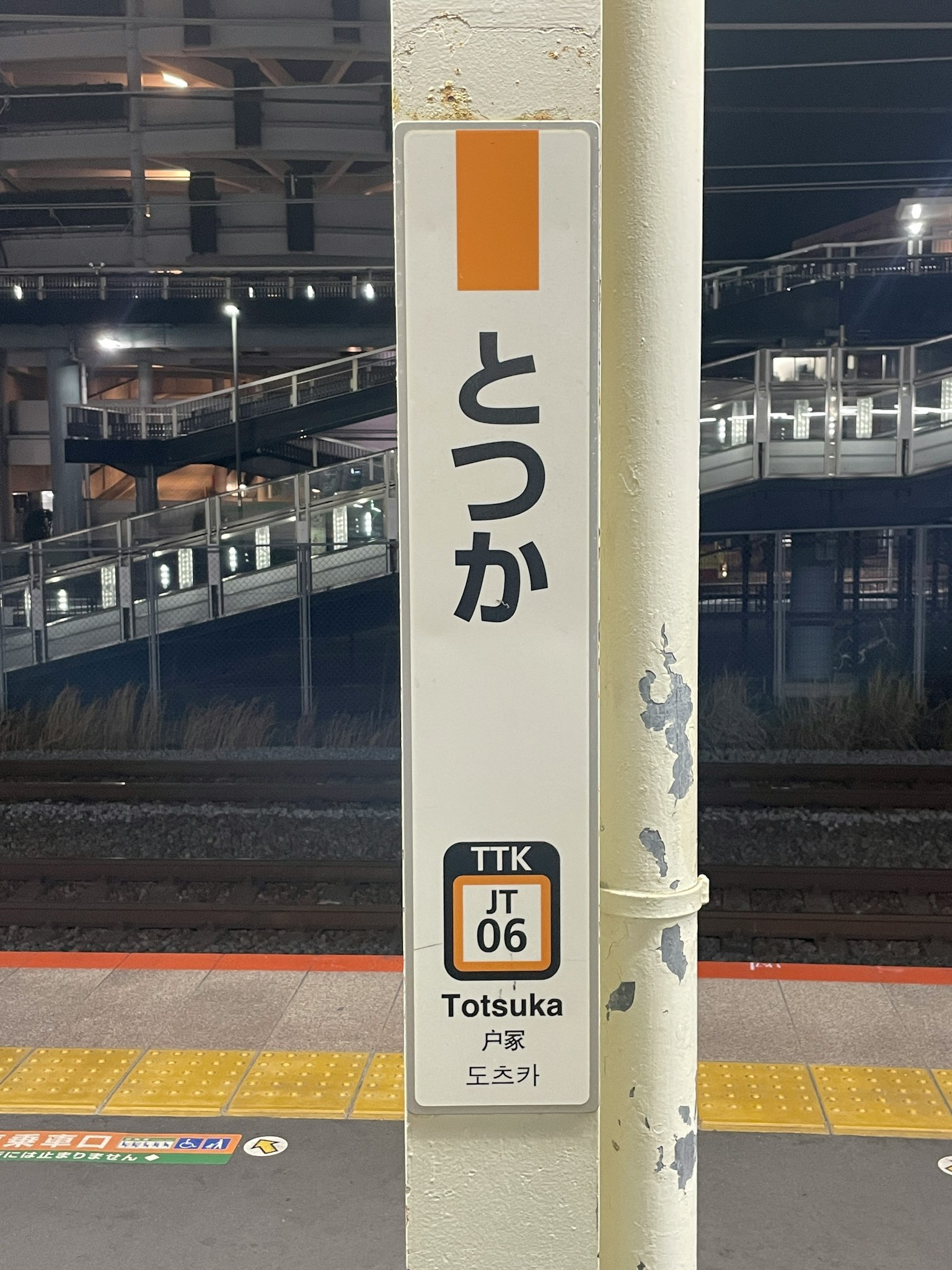 Tanda stasiun Totsuka di platform malam