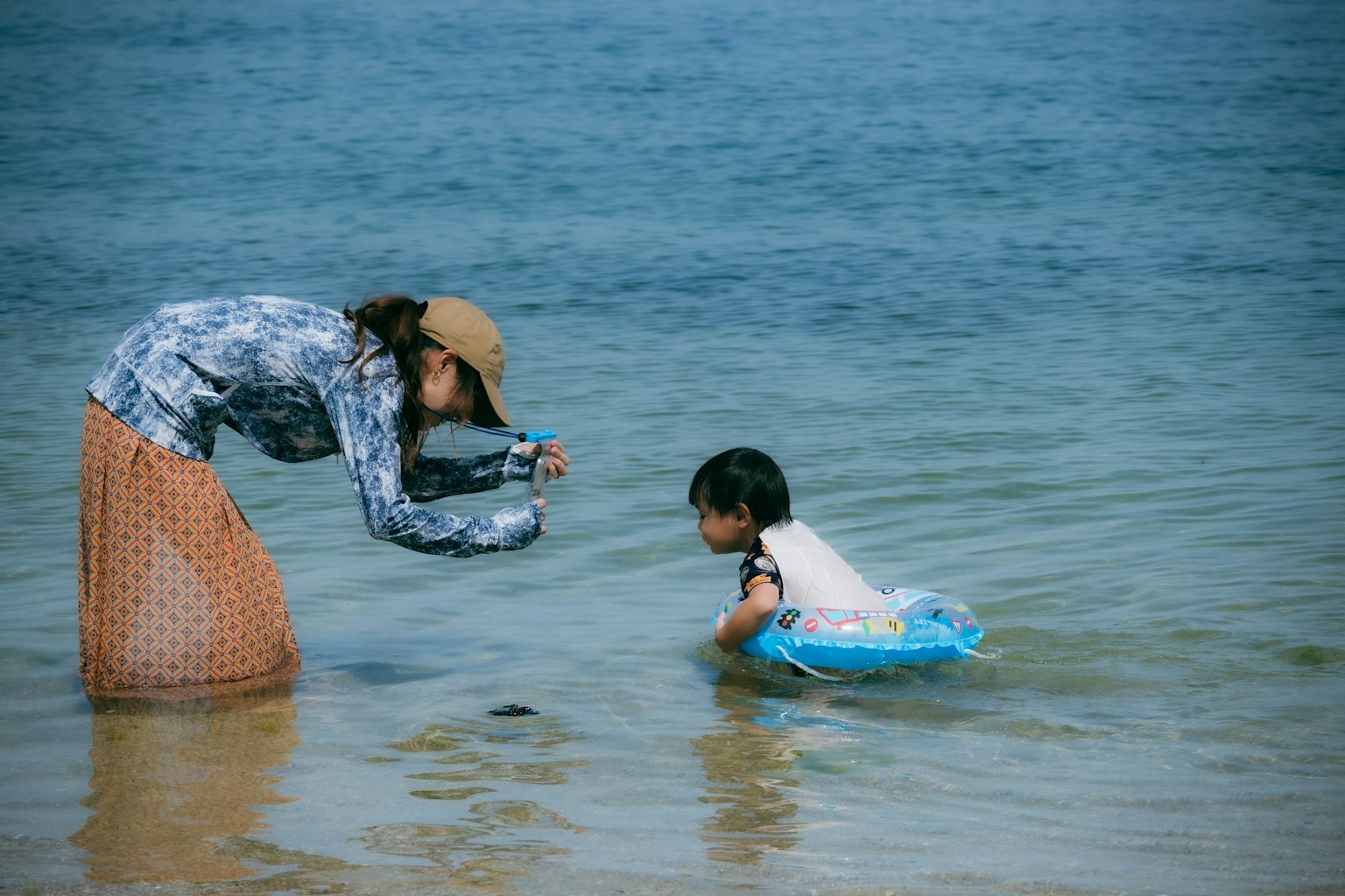 海で遊ぶ子供とカメラを構える母親