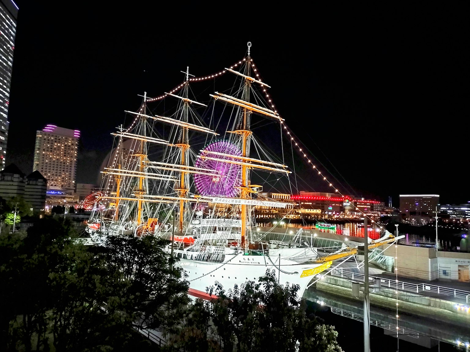 เรือใบสวยงามที่มีแสงไฟกลางคืนพร้อมแสงไฟเมือง