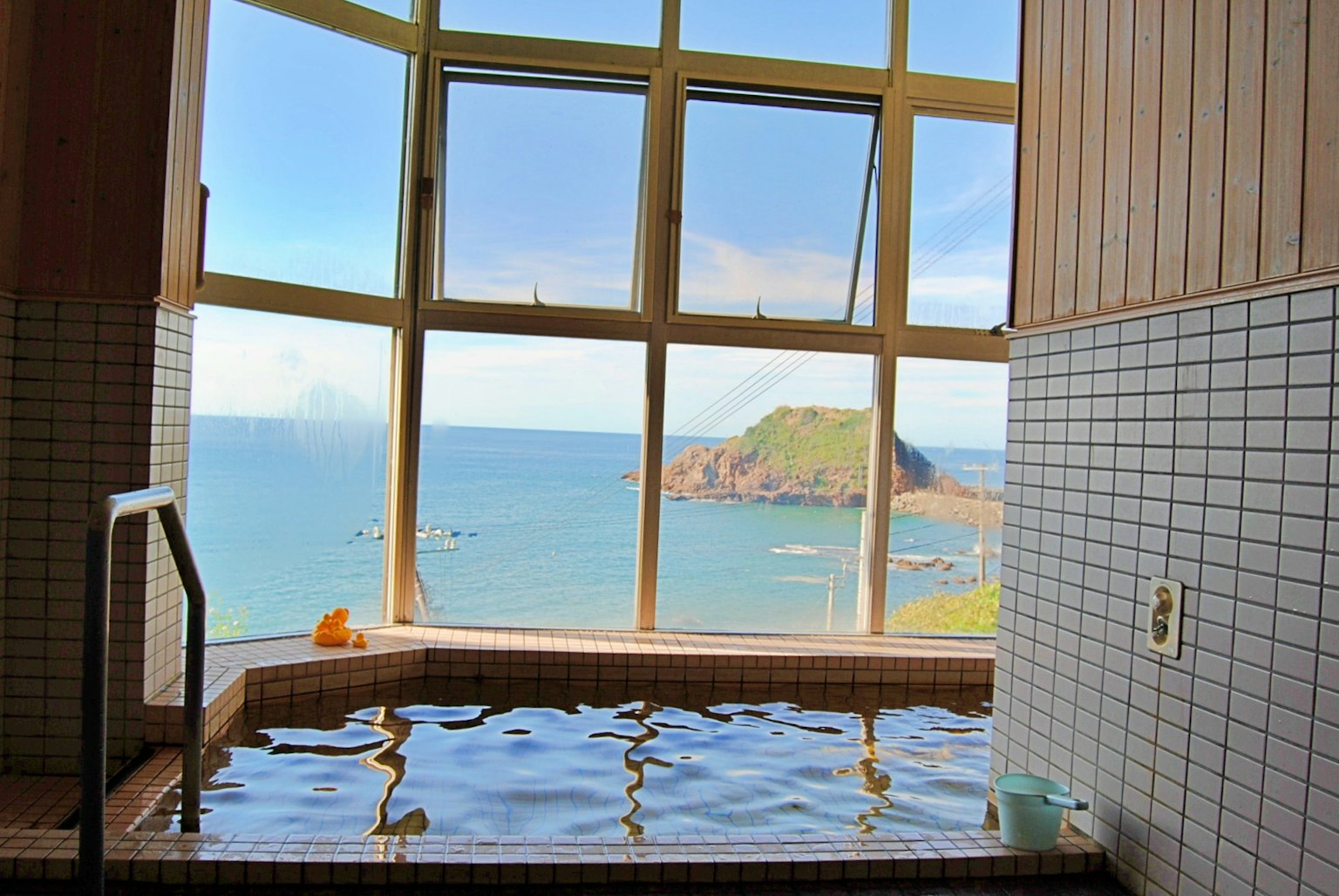 Baño termal interior con vista al mar luz natural que entra por las ventanas