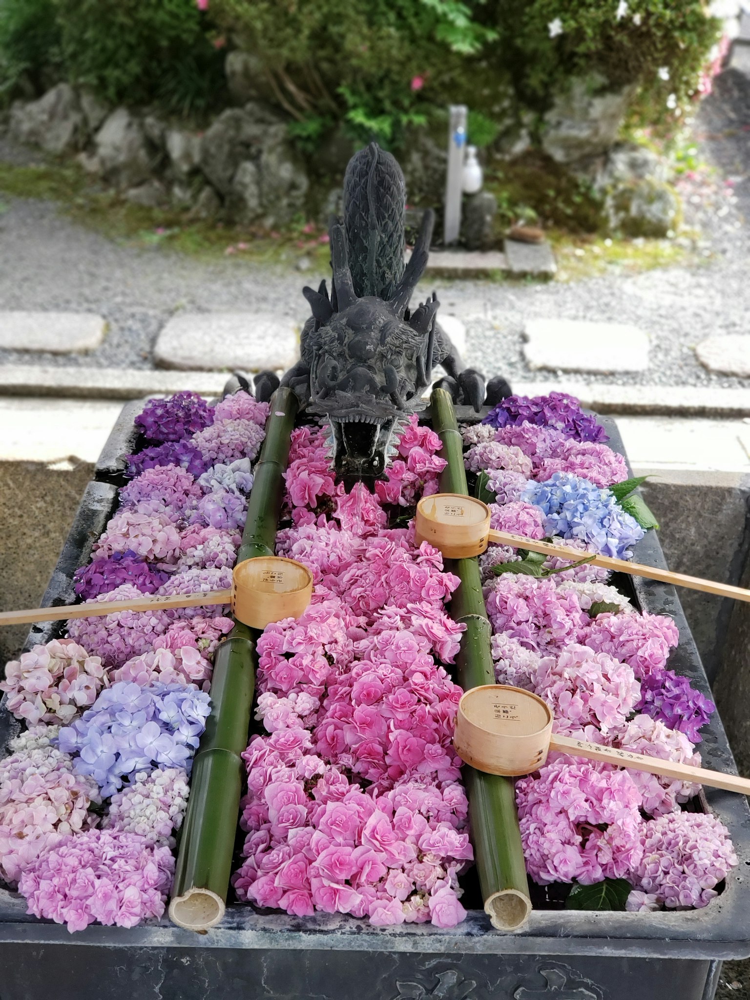 A basin filled with colorful flowers and a dragon sculpture above it