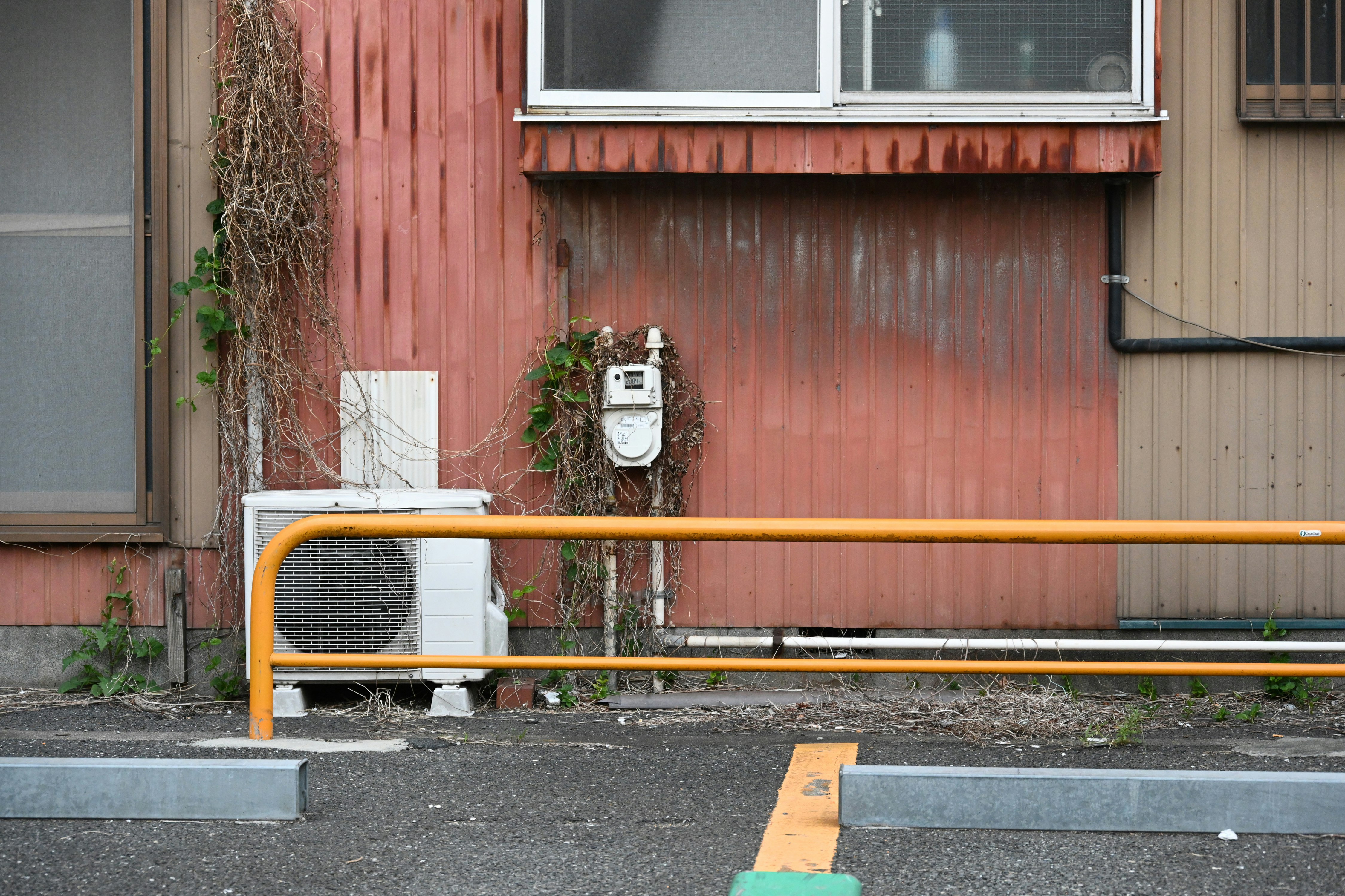 赤い外壁の建物前にあるオレンジの手すりと街角の小物