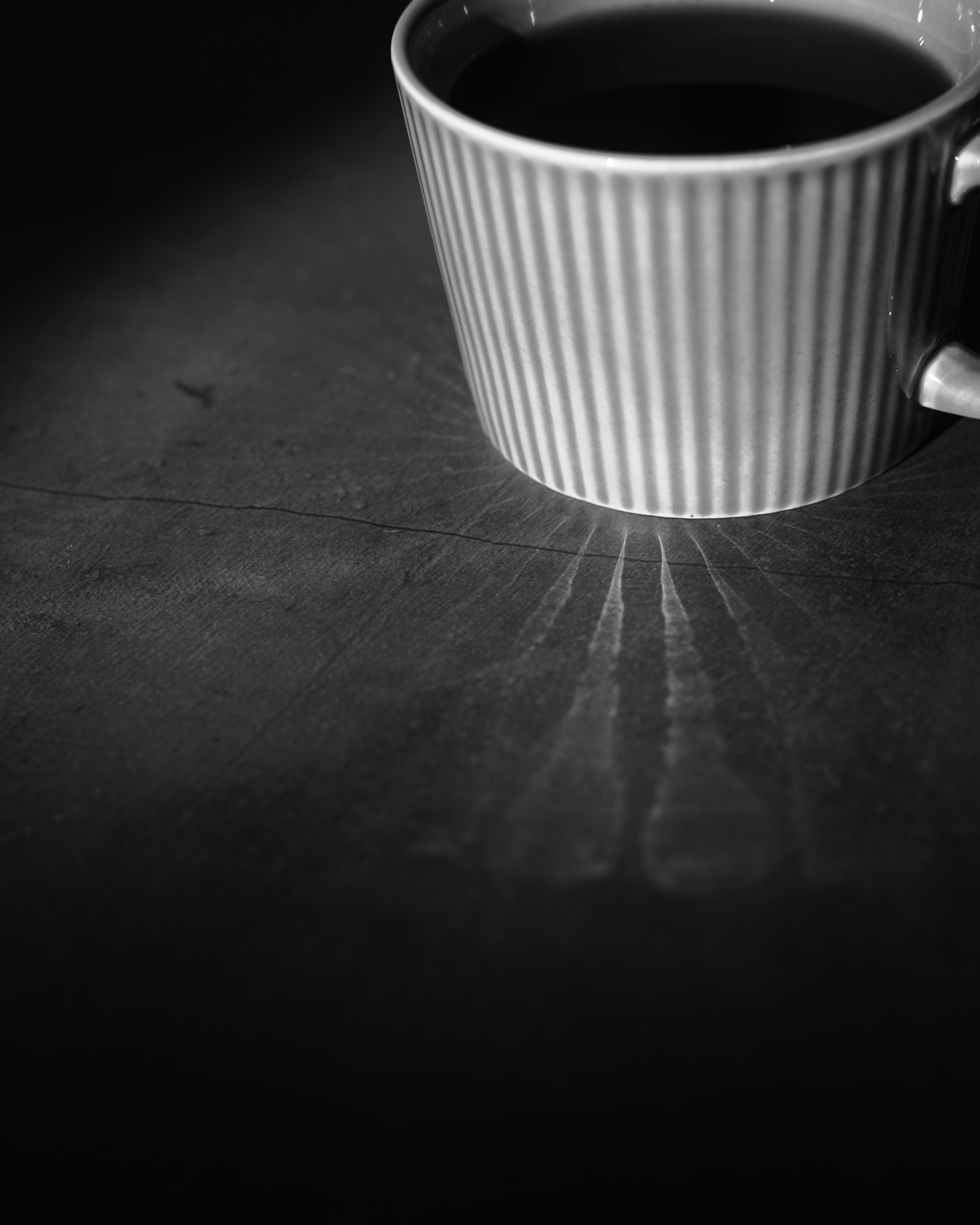 ถ้วยกาแฟลายทางสีขาวบนพื้นหลังมืดที่สร้างเงา